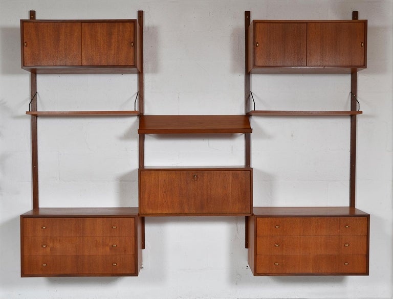 This highly versatile and functional “Royal System” was designed by Poul Cadovius in 1948. This particular piece is quintessentially Mid-century Modern being the first generation with orange-slice brass handles. 
Simply hung on brass pins and