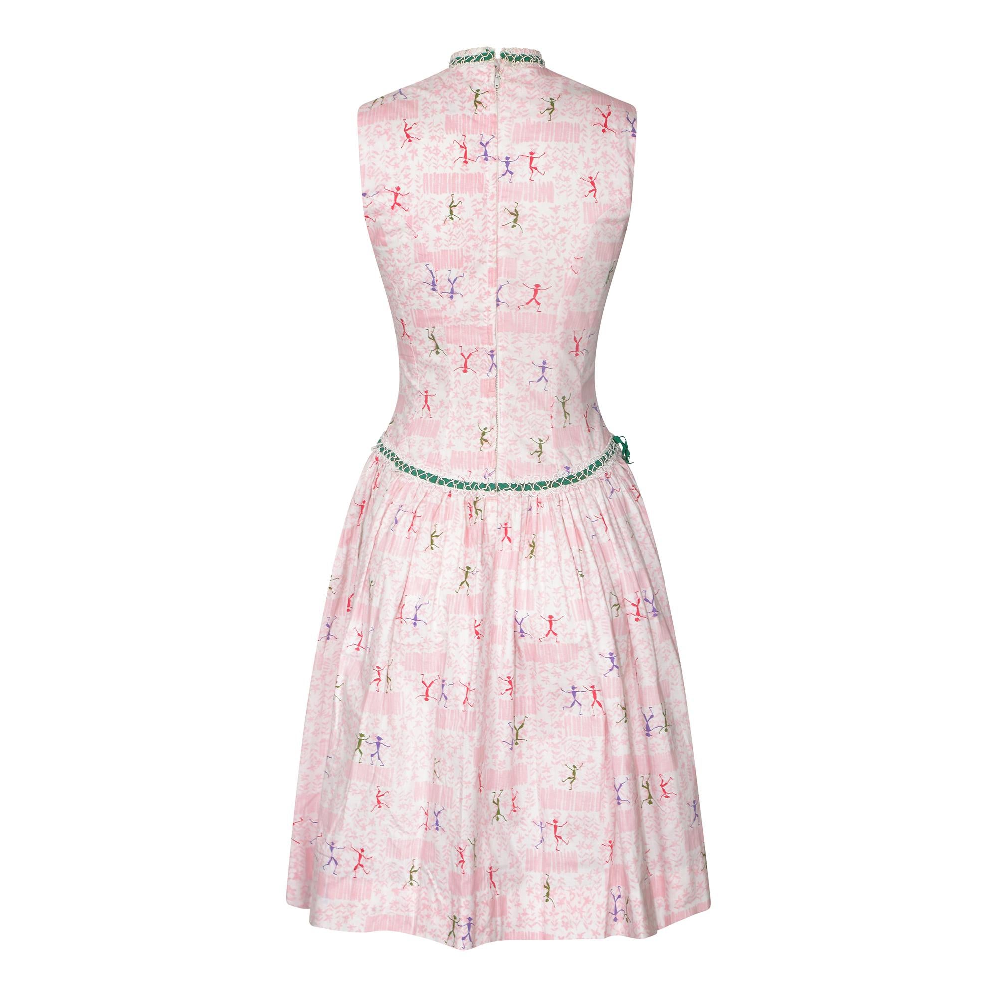 This is an absolutely super original 1950s dress with the label Teena Paige Fashions. The print really is a delight and features a pink floral garden scene background with a duo and sometimes a trio of dancing man figures in purple, green and red.