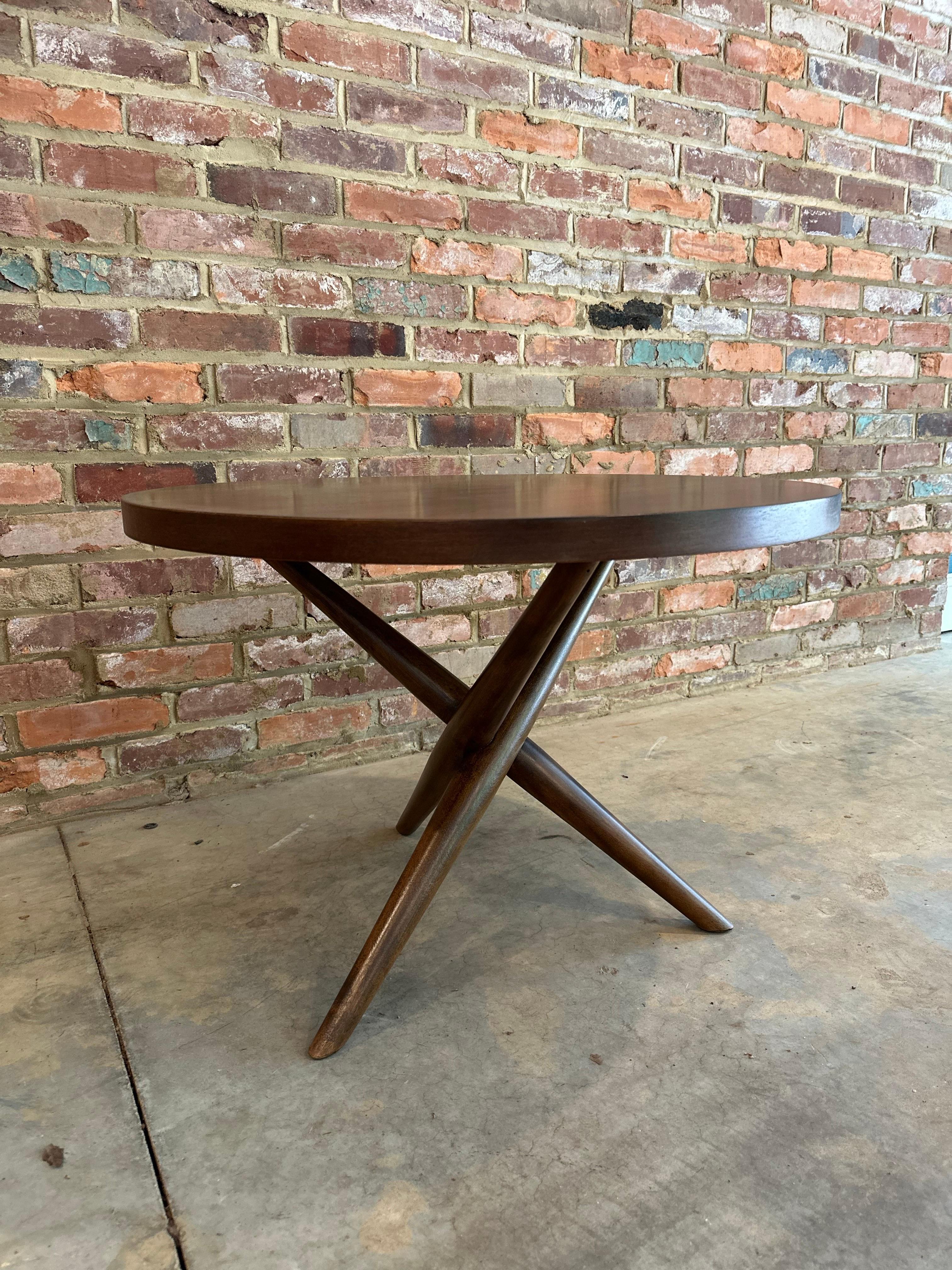 Occasional table with round top supported by a criss-cross tripod base. Model no. 1742. By T.H. Robsjohn-Gibbings for Widdicomb. American, circa 1953. Very sculptural splayed tripod form, yet strong and sturdy. Versatile size; could be used as a