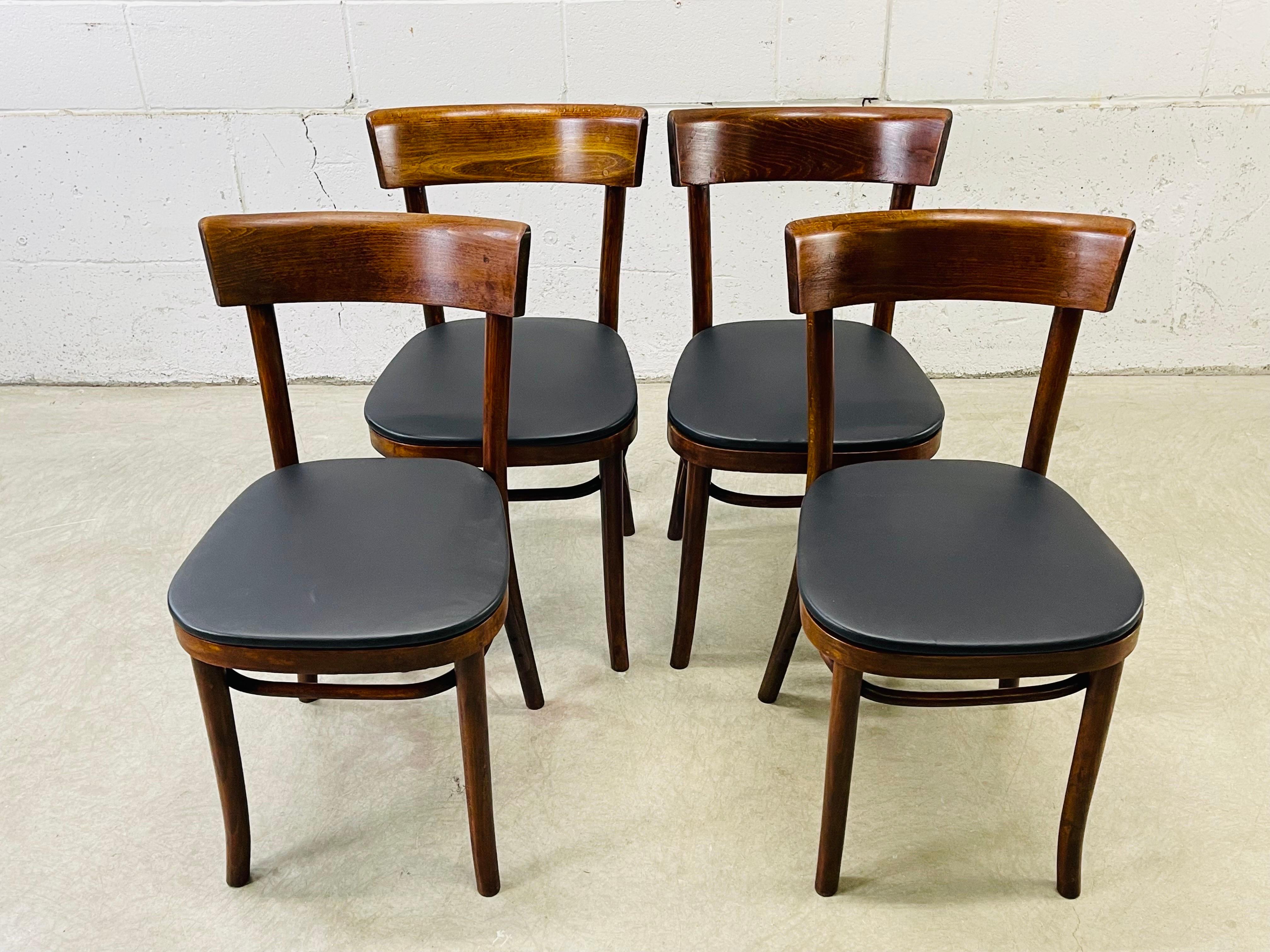 Vintage 1950s set of 4 Thonet style bentwood and curved back maplewood dining chairs. The chairs have been fully restored and have new black naugahyde seats. The maple wood has a dark stain. No marks.