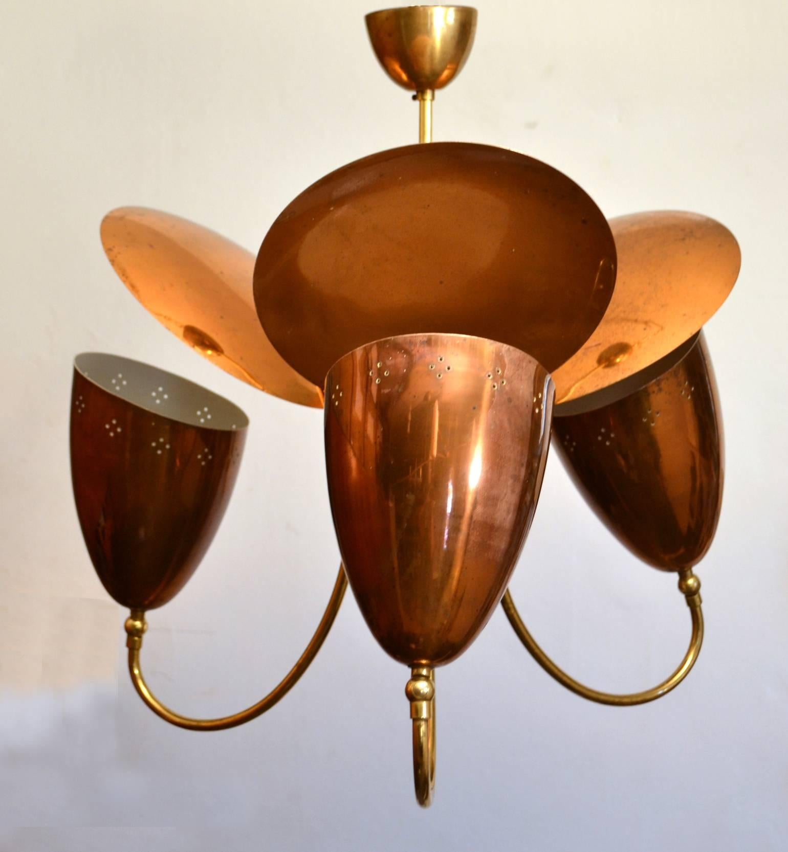 Original and charming three-arm chandelier with three adjustable perforated up-lighter shades in copper and disk-shape reflectors, connected by a brass frame and fixtures.
Similar chandeliers were produced by Lightolier, Angelo Lelli for Arredoluce