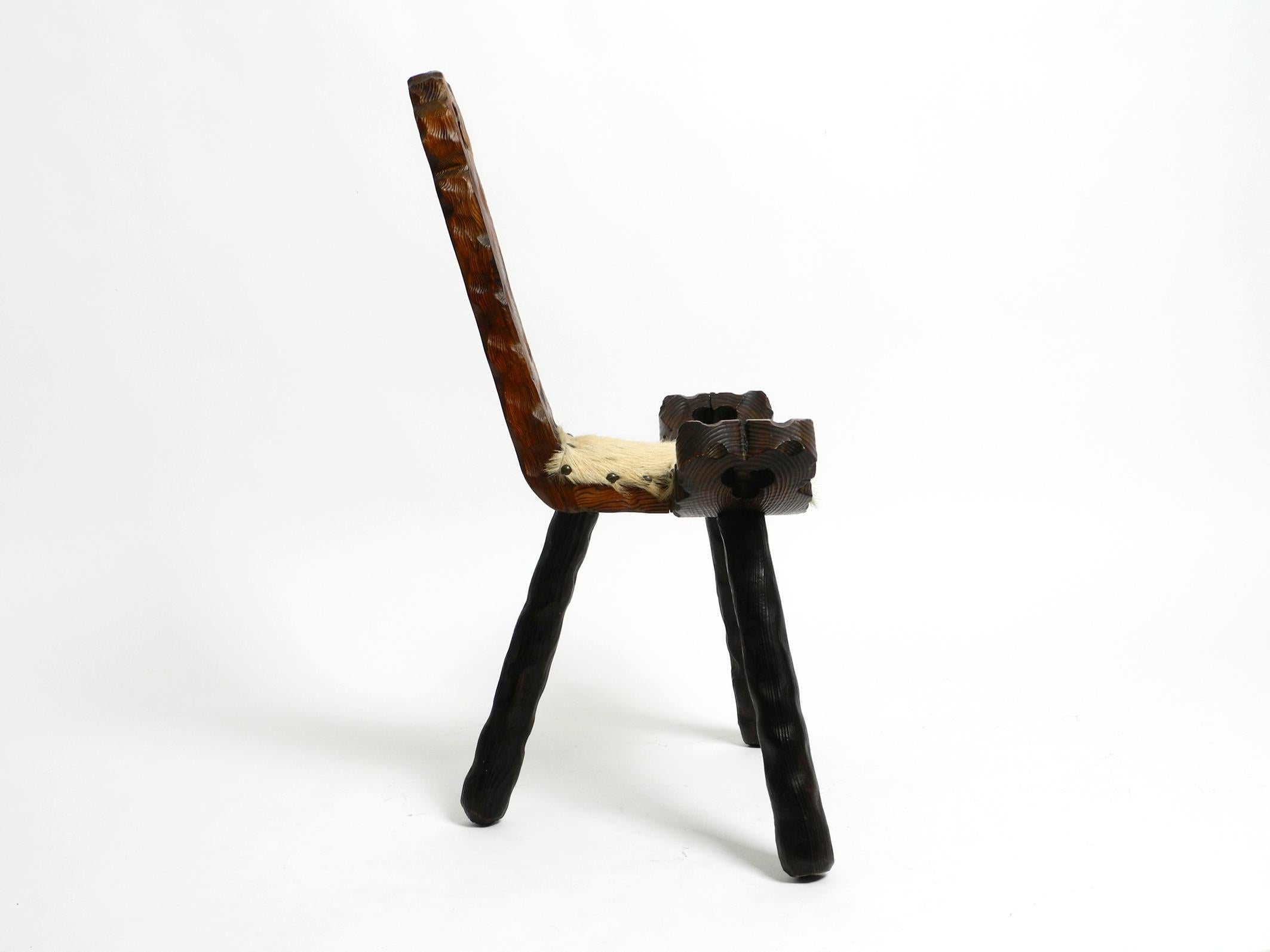 Mid-Century Modern 1950s three-legged stool made of solid wood in black-brown with cowhide seat For Sale