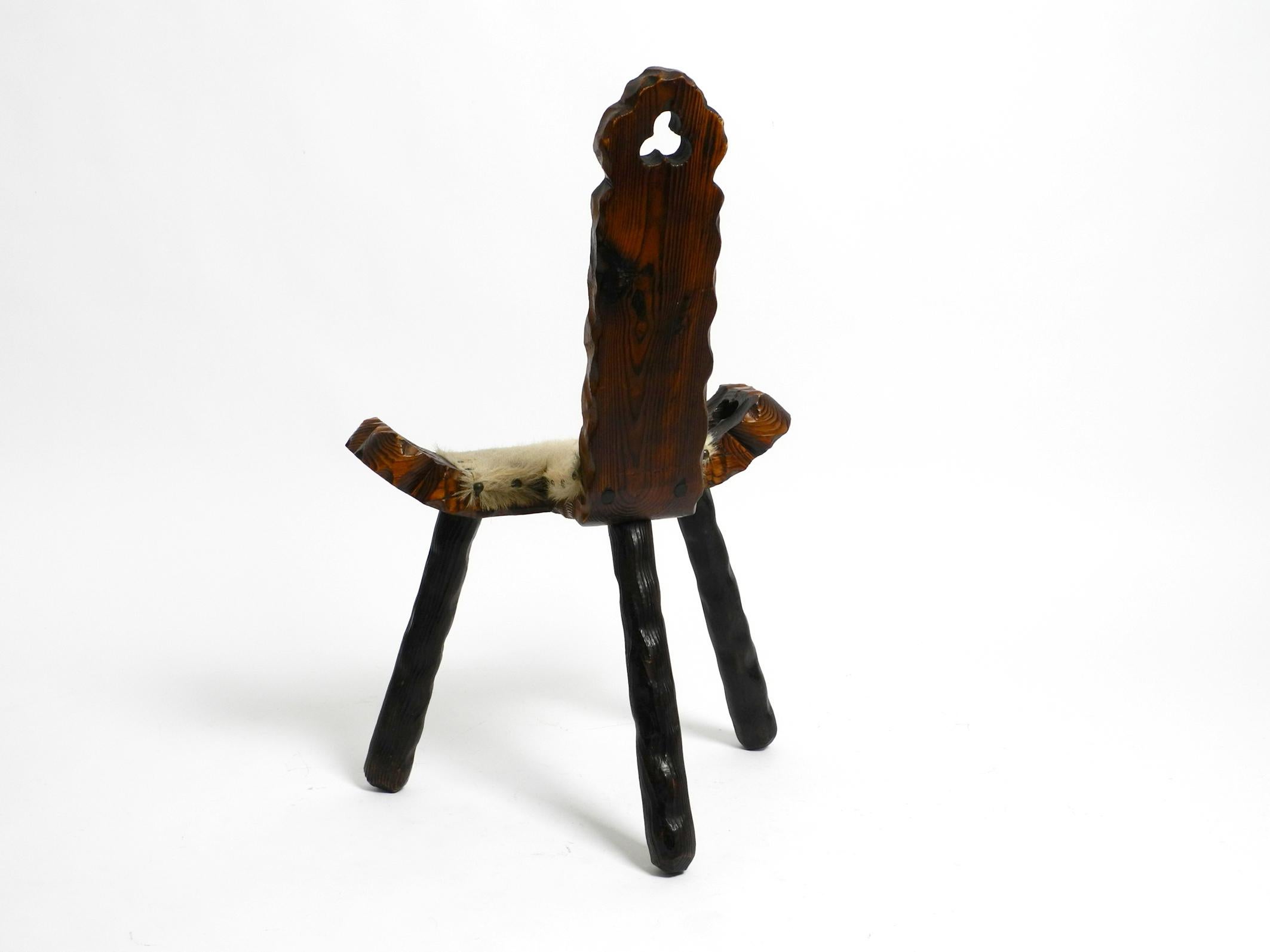 European 1950s three-legged stool made of solid wood in black-brown with cowhide seat For Sale