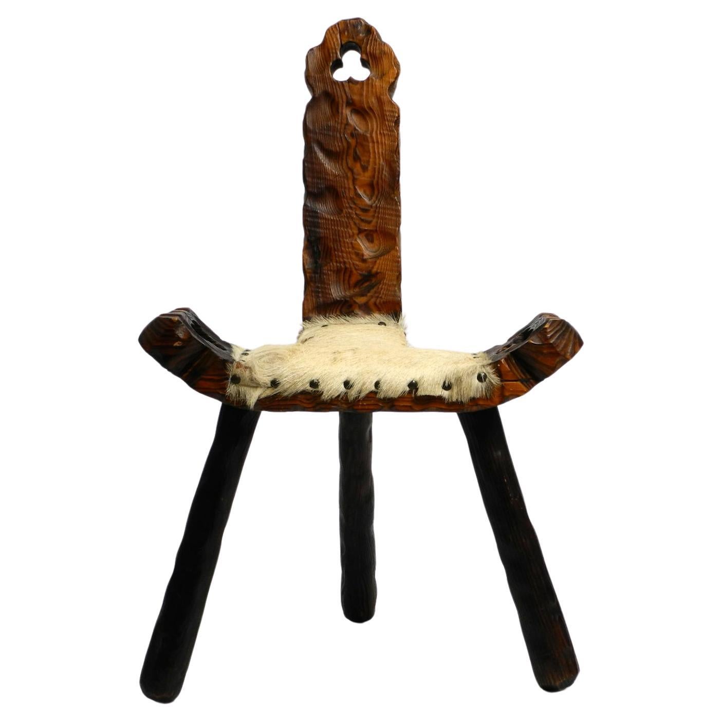 1950s three-legged stool made of solid wood in black-brown with cowhide seat For Sale