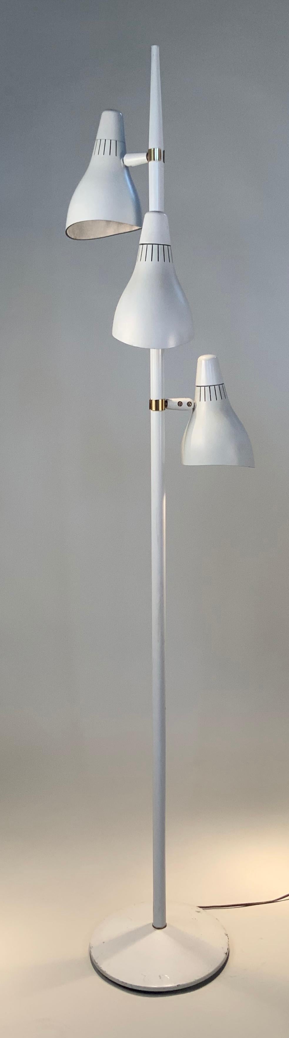 A very well designed vintage 1950s floor lamp with three lights, fully adjustable, mounted with brass fittings on a tall stem. Beautifully shaped conical shades with integrated switches at the top of each vented shade. Marked with Lightolier's
