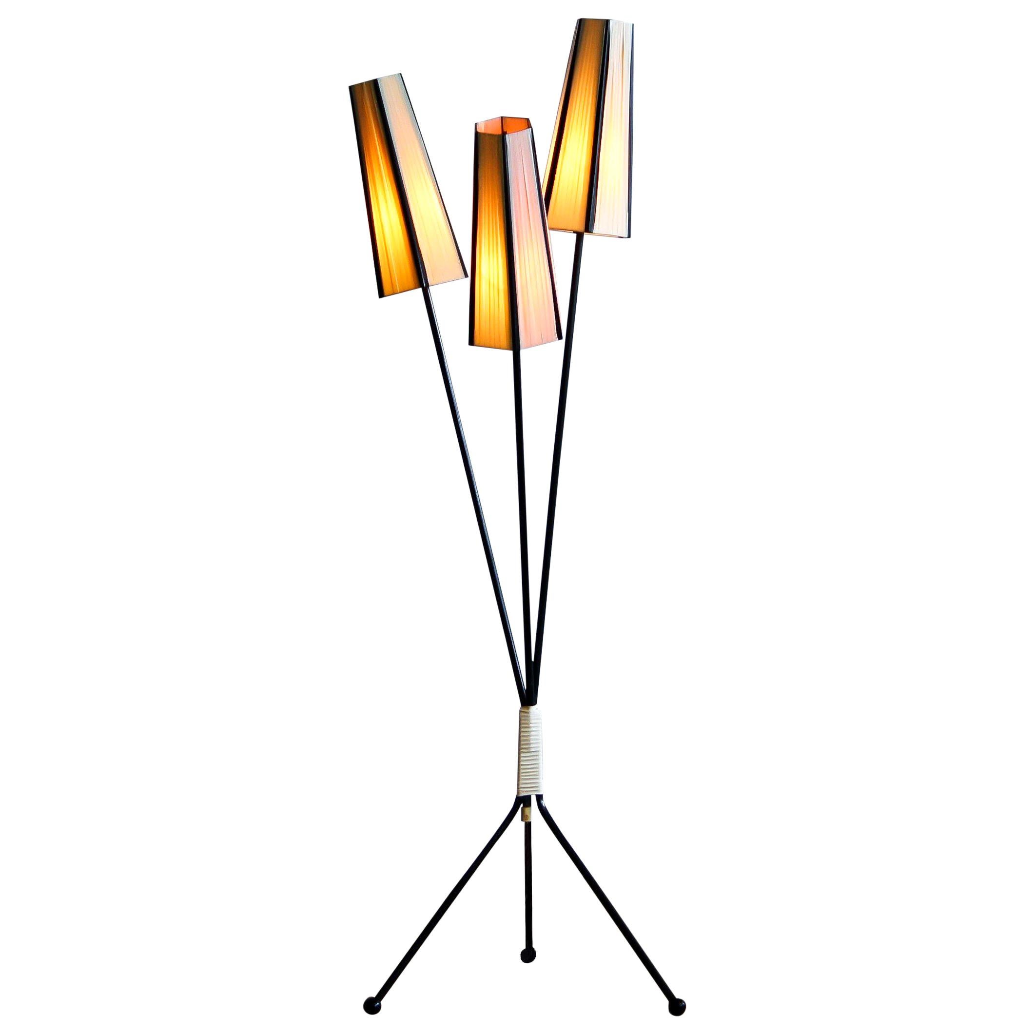 Floor lamp with two off-white and one salmon polyester fabrics covers from the 1950s.
The caps are lined with black cords.
The lamp stands on a black metal three-leg rest. It is in good condition.
Period 1950s.
Dimensions: H 138 cm, ø 45.