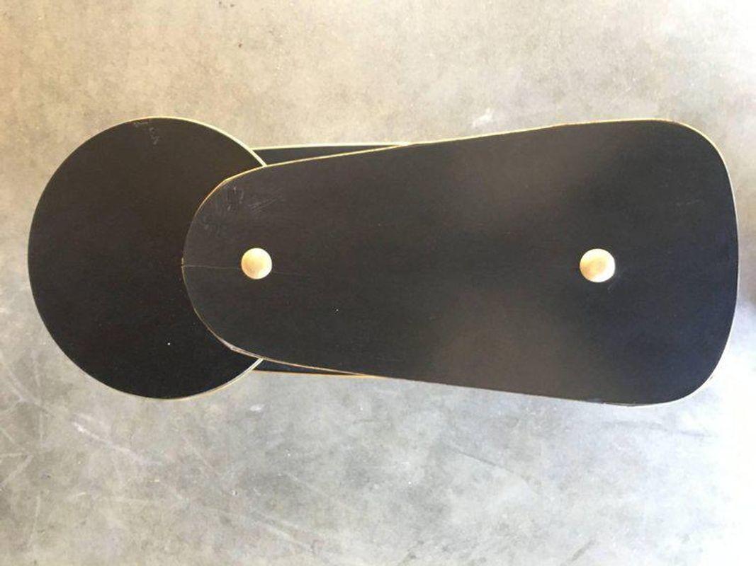 Conjunto de tres mesas auxiliares de mediados de siglo con centro de diseño de arte en cuerda y tableros de fórmica negra con adornos de latón y patas cónicas. Hay dos mesas altas y una mesa baja.