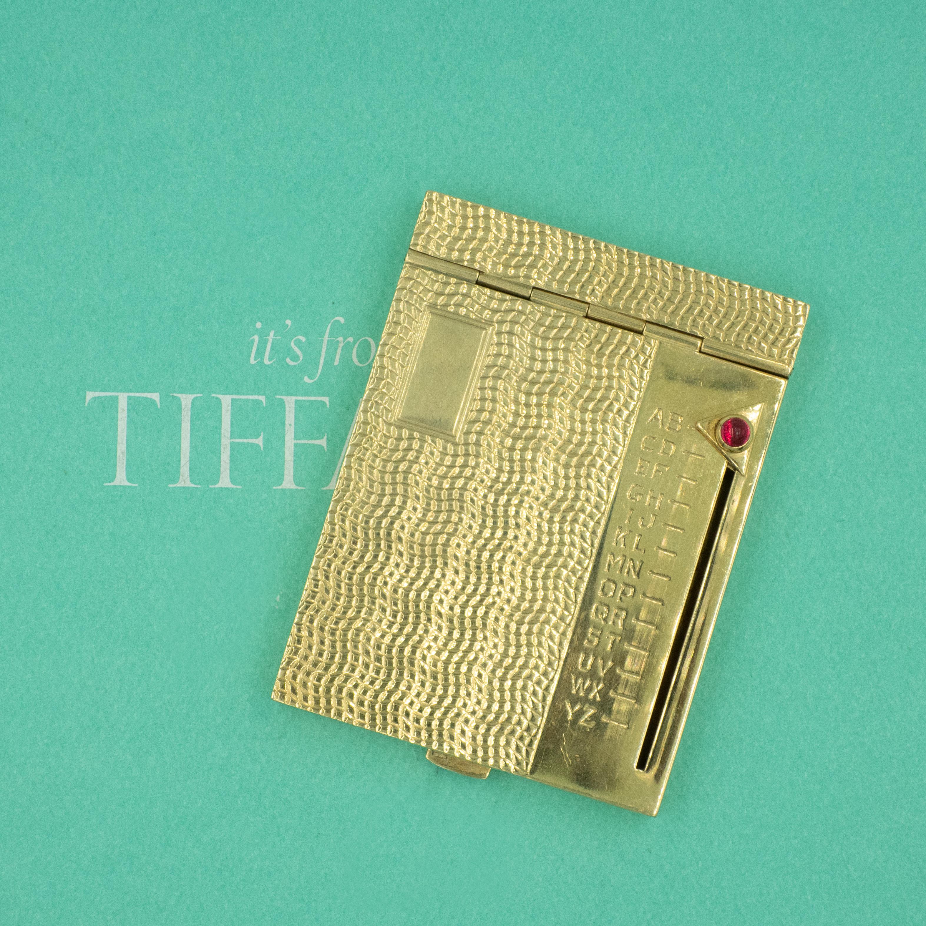 Rare Tiffany & Co. Rolodex from the 1950s, is a highly collectible piece in unused condition. The rolodex is crafted in 14k yellow gold with pattern. A cabochon ruby is set on the page selection slide. When lever is pressed, it opens up to selected