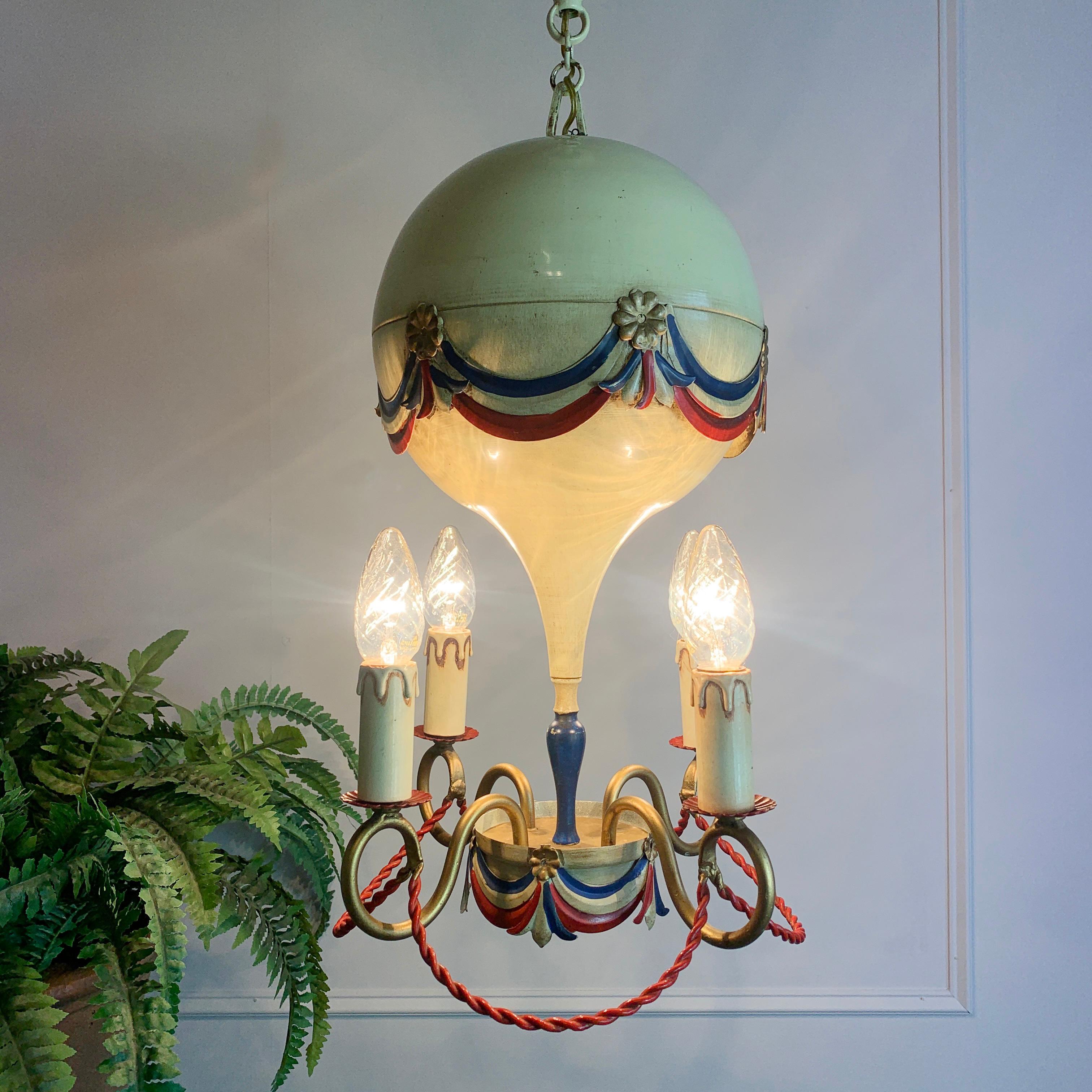Mid century toleware hot air balloon chandelier, c 1950’s
This stunning light is a rare find in such great original condition
The main balloon body of the light is in full metal with original hand painted swags and rosettes in red, white, blue &