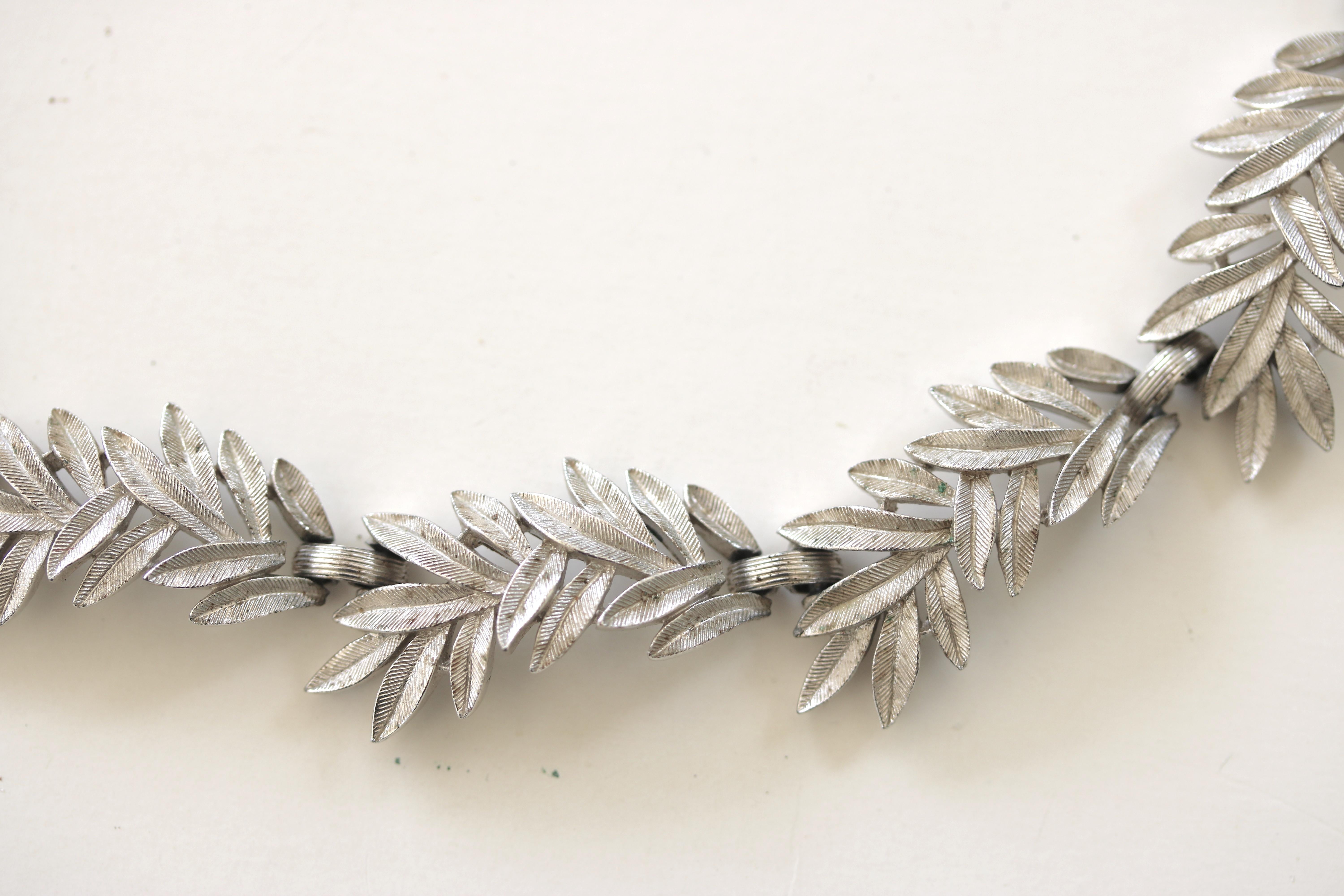 A Vintage articulated brushed silver tone leaf necklace and matching earrings by famed Trifari.  circa 1950s.
The delicate appearance of each asymmetrical leaf with a ribbed pattern design has 10 linked panels on the necklace a chain for