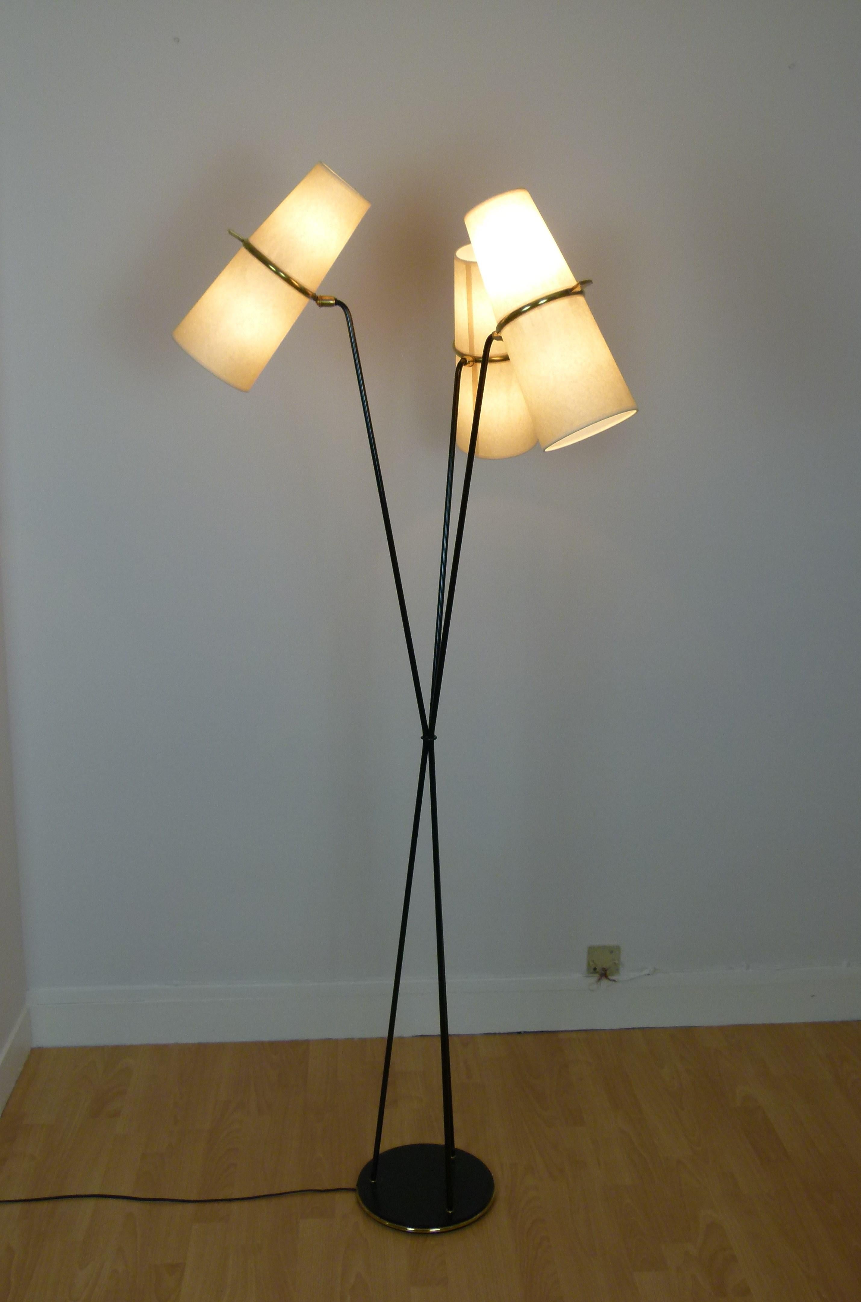 Floor lamp in black lacquered metal and brass, composed of a circular base in black lacquered cast iron, set with a brass ring on which are arranged three lacquered metal sconces, which intertwine in their middle.
Each arm has at the end, a brass