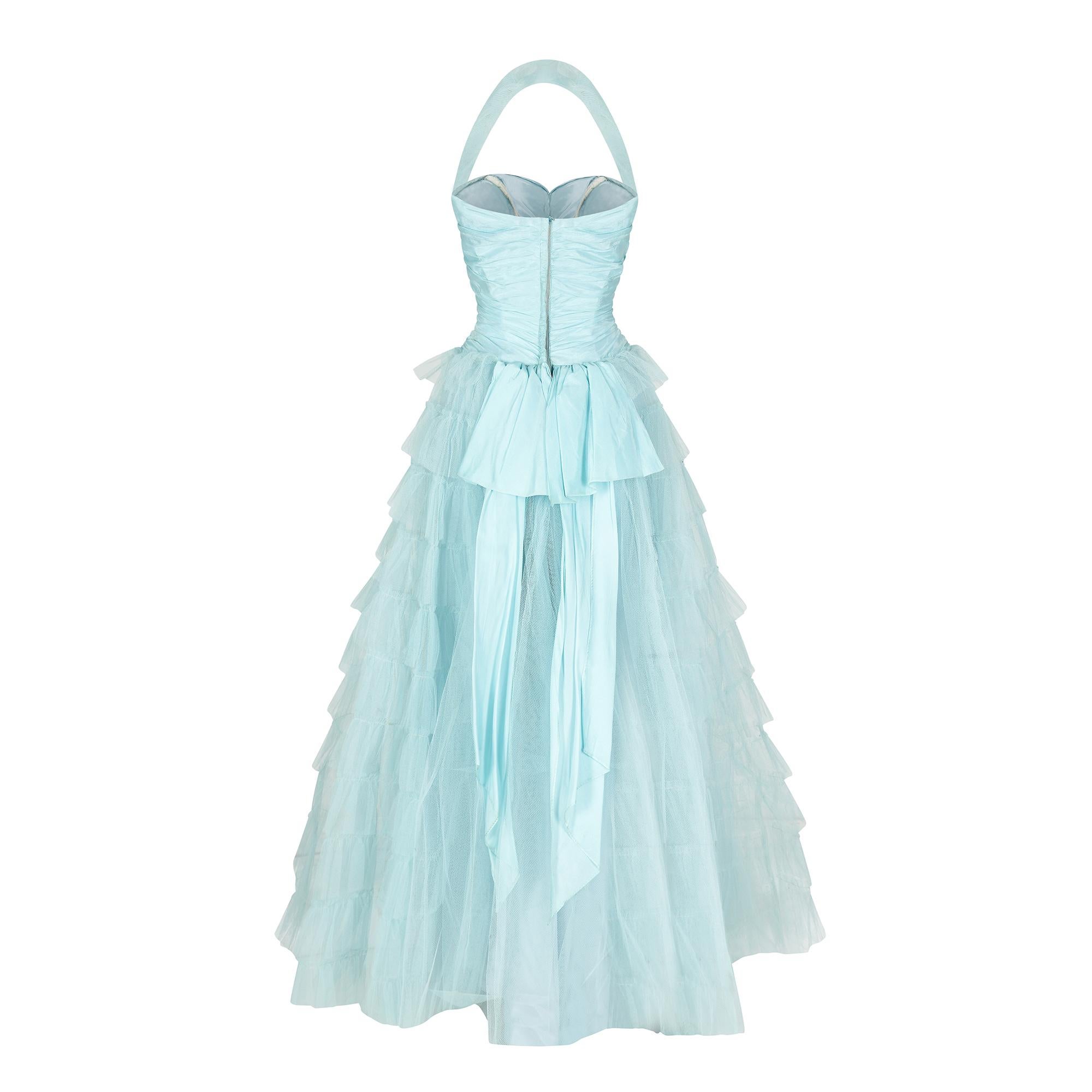 This original 1950s turquoise and net prom dress is a real show-stopping, fairy tale piece. It reminds us of the Disney Princess dress worn by Cinderella at the ball. 

There are three layers to the skirt; an acetate underskirt, over-laid with a