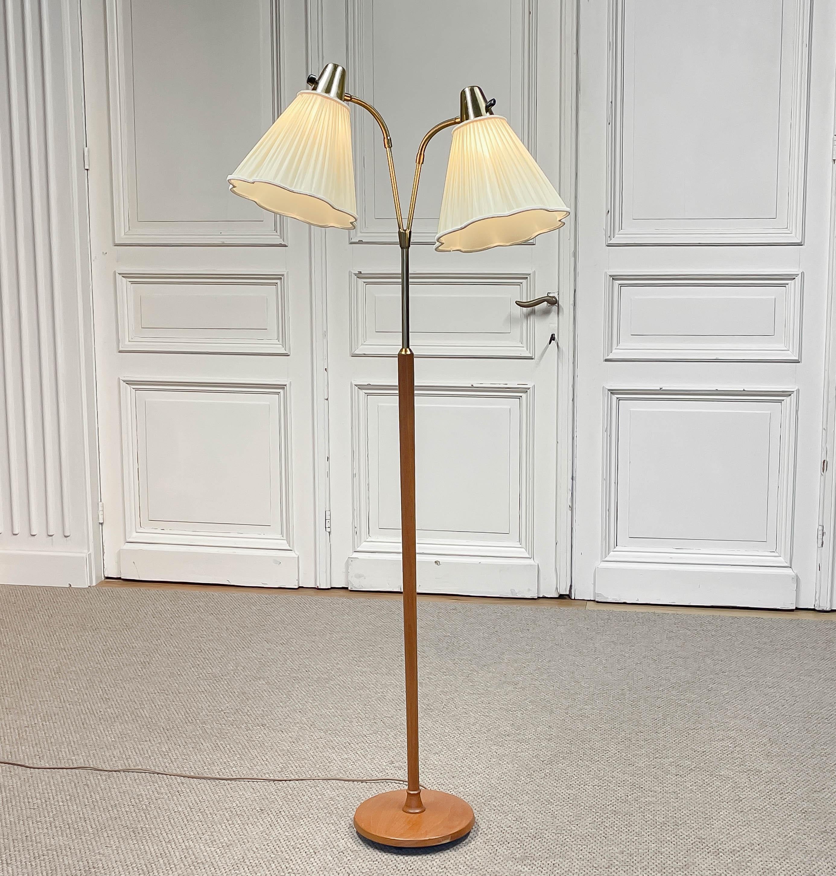 Elegant design scandinave avec des abat-jours en tissu plissé de couleur vanille montés sur des bras en laiton réglables, permettant à chaque lumière d'être actionnée individuellement.
La lampe repose sur une tige et une base en teck massif,