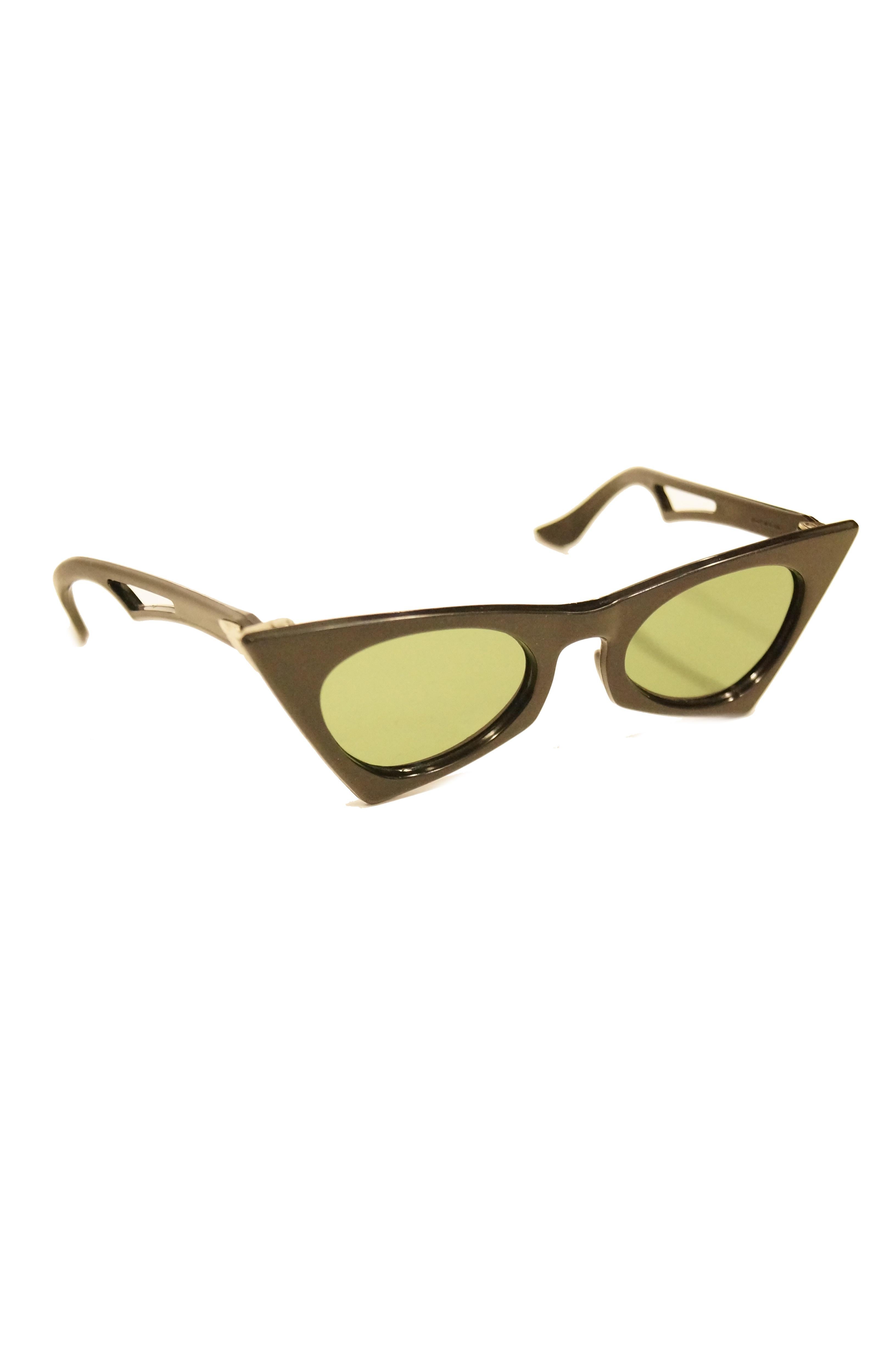 Iconic edgy sunglasses straight from the 50s! These striking frames have a bold green lens thats contrasted by glossy black frames. The frames are amazing, with a sharp, trapezoidal, butterfly - like shape on the sides, and with a straight top that