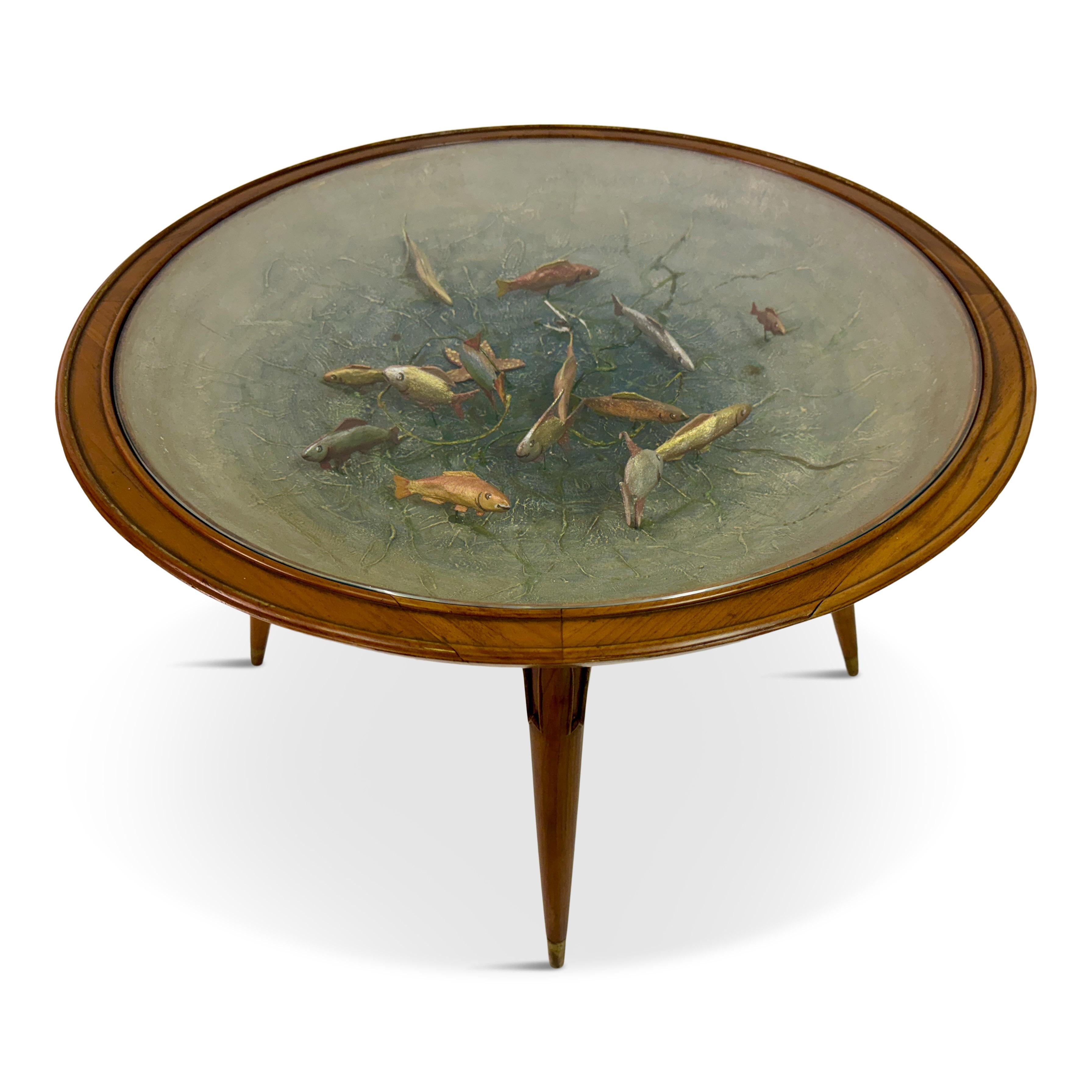 Cette table est un exemple remarquable du design des meubles du milieu du siècle, caractérisé par son élégant cadre en bois et la mise en place de modèles de poissons à l'intérieur du corps de la table. Il présente un plateau rond en verre avec une