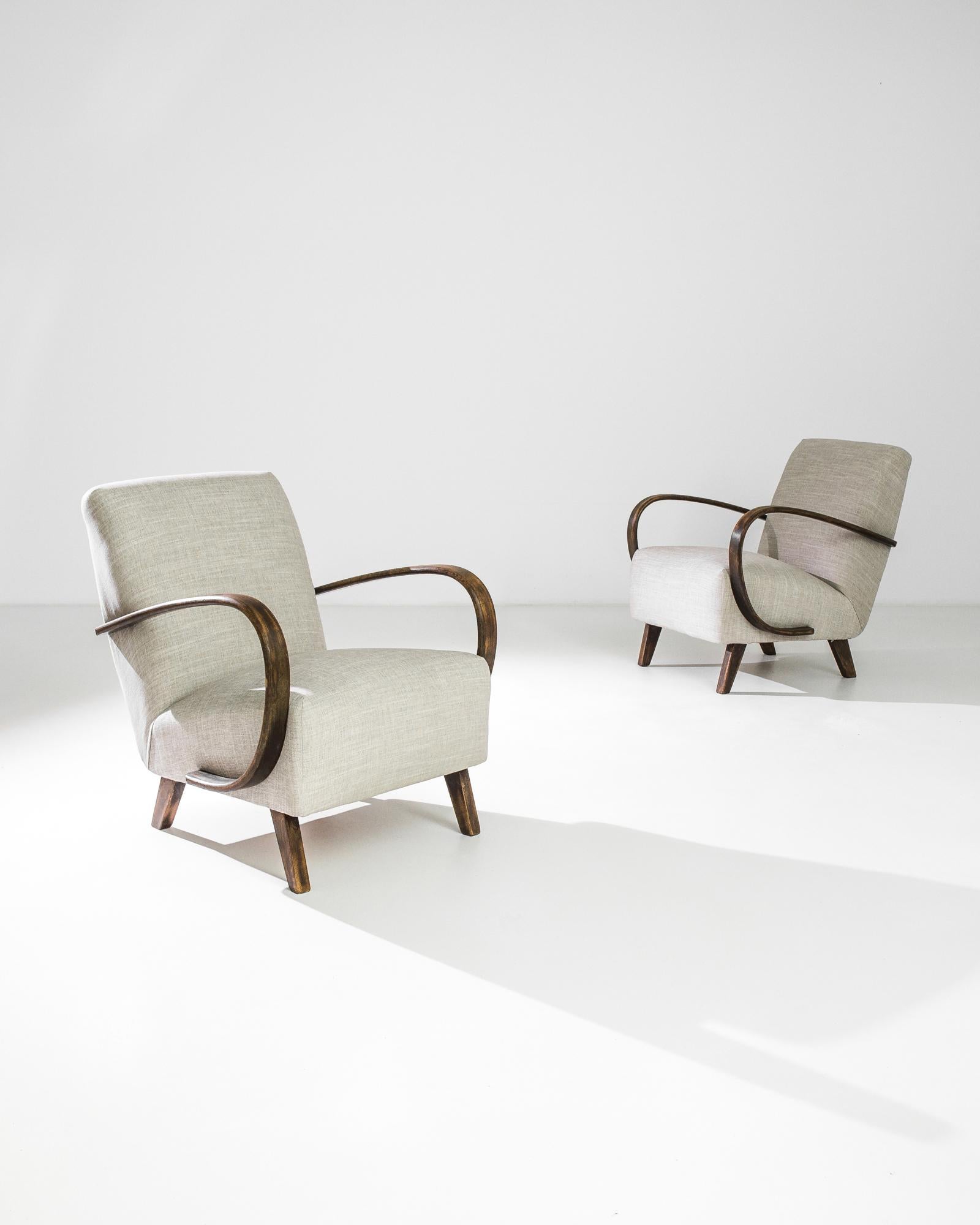 A pair of upholstered armchairs by Czech furniture designer J. Halabala. Made in the 1950s, the eye-catching silhouette and comfortable design has an enduring appeal. Influenced by Mid-Century Modern and Art Deco design, a deep upholstered seat upon
