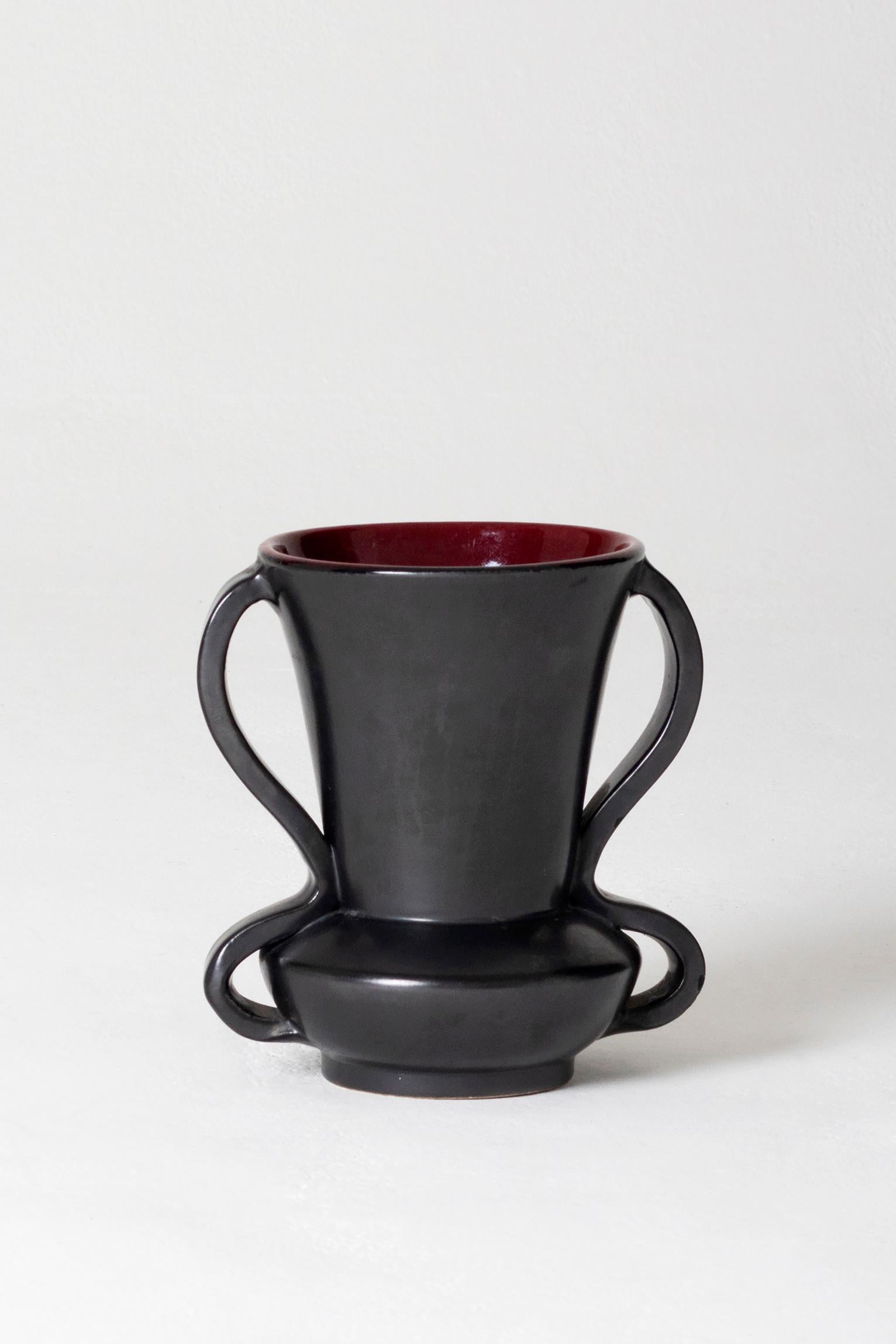 A black ceramic vase, with handles and a burgundy interior
Vallauris, France, circa 1950.