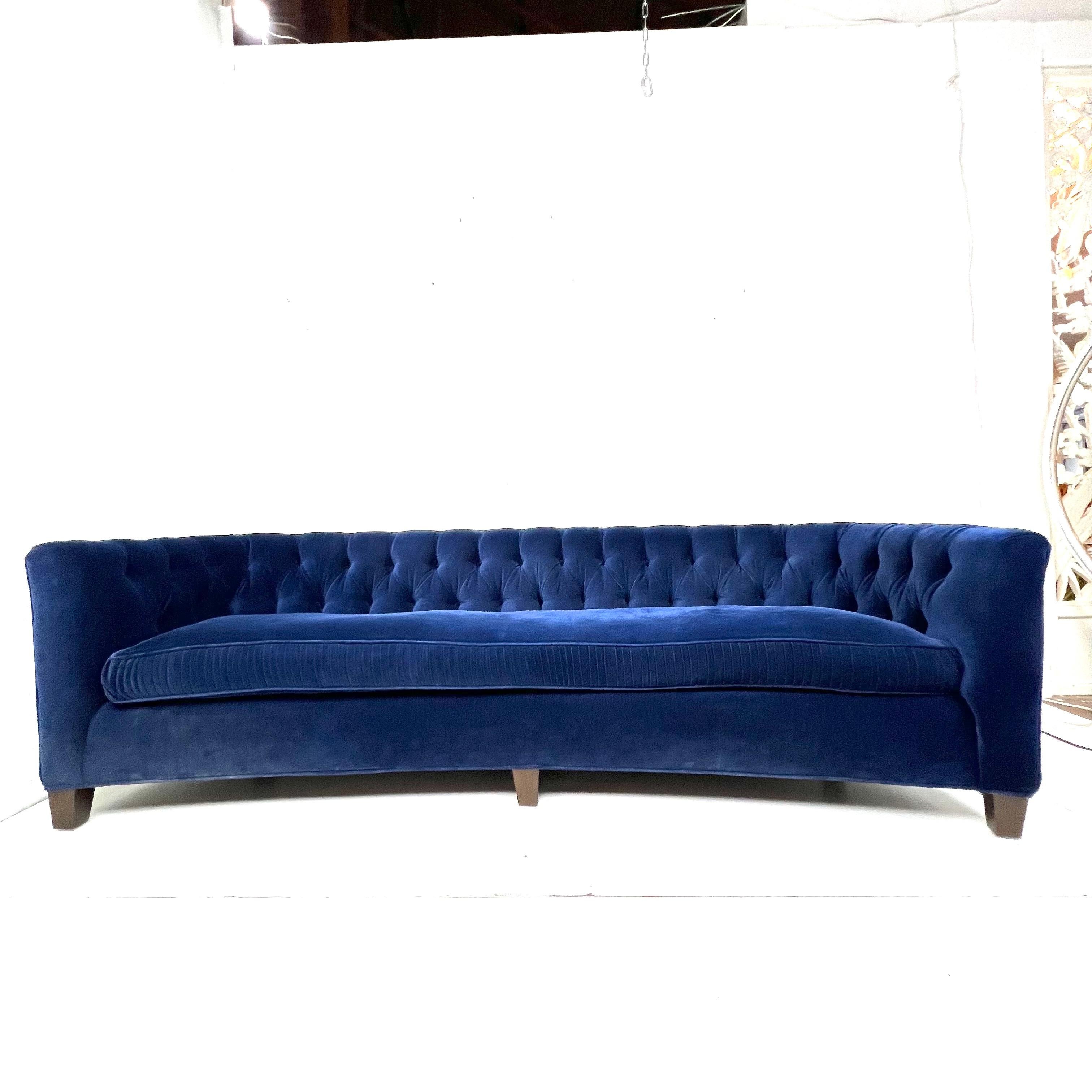 1950's tufted back sofa featuring a gently curved classic design. Upholstered in button tufted blue velvet fabric. Down wrapped long seat cushion and walnut legs. Sturdy and in good condition with some cosmetic wear consistent with age and use. New