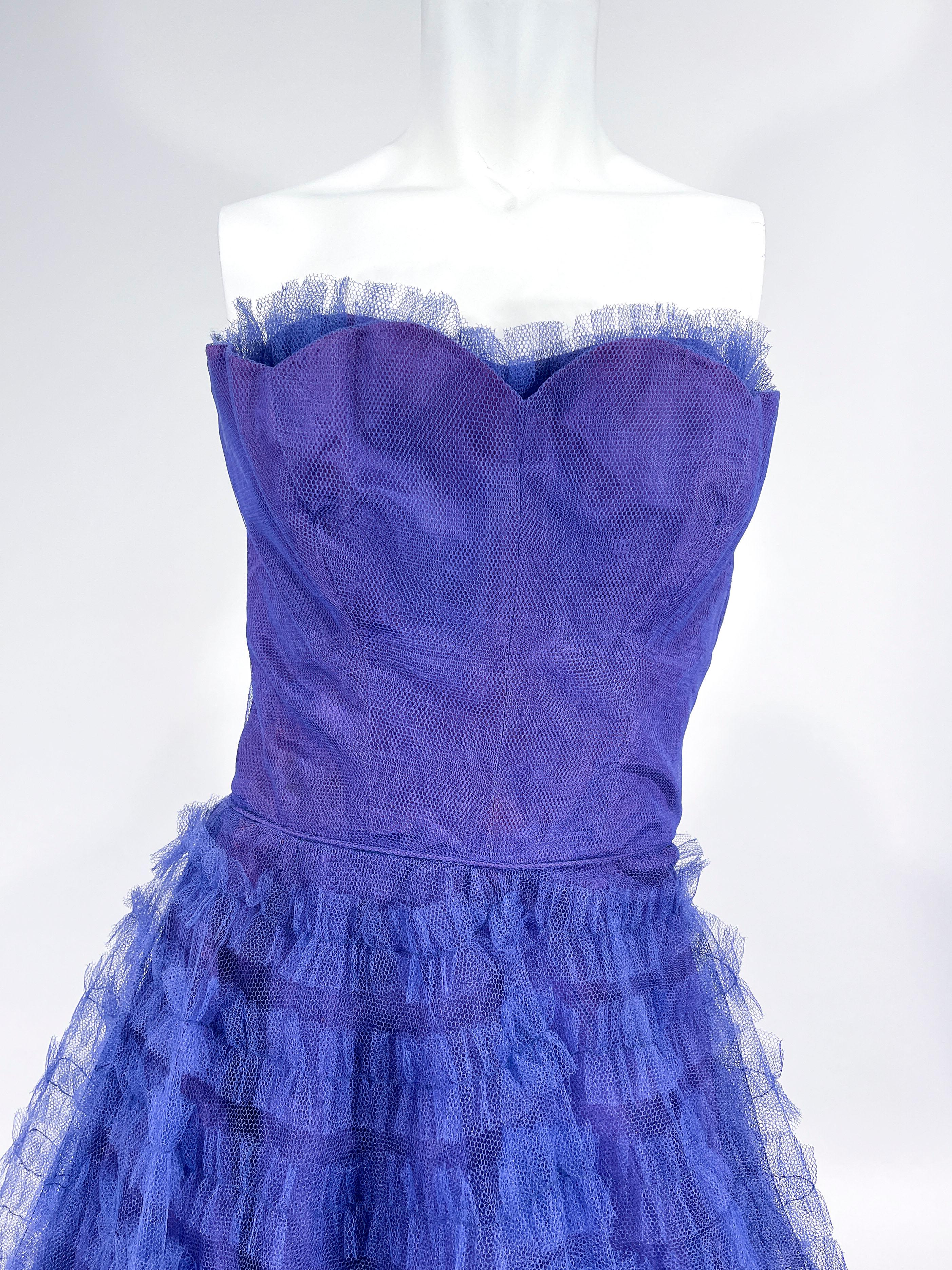 1950s velvet/purple tulle party dress featuring a strapless fitted and boned bodice that has a sweetheart neckline adorned with ruffled tulle. The full skirt has multiple tiers of ruffled tulle onto a matching tulle base. This dress is fully lined
