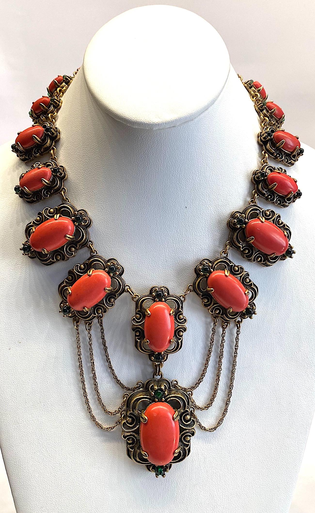 An intricate and substantial Victorian Revival necklace from the 1950s. Each of the five different size medallion links are beautifully cast in detail and patinated for an antique gold finish. Additionally, they are set with a large oval coral glass