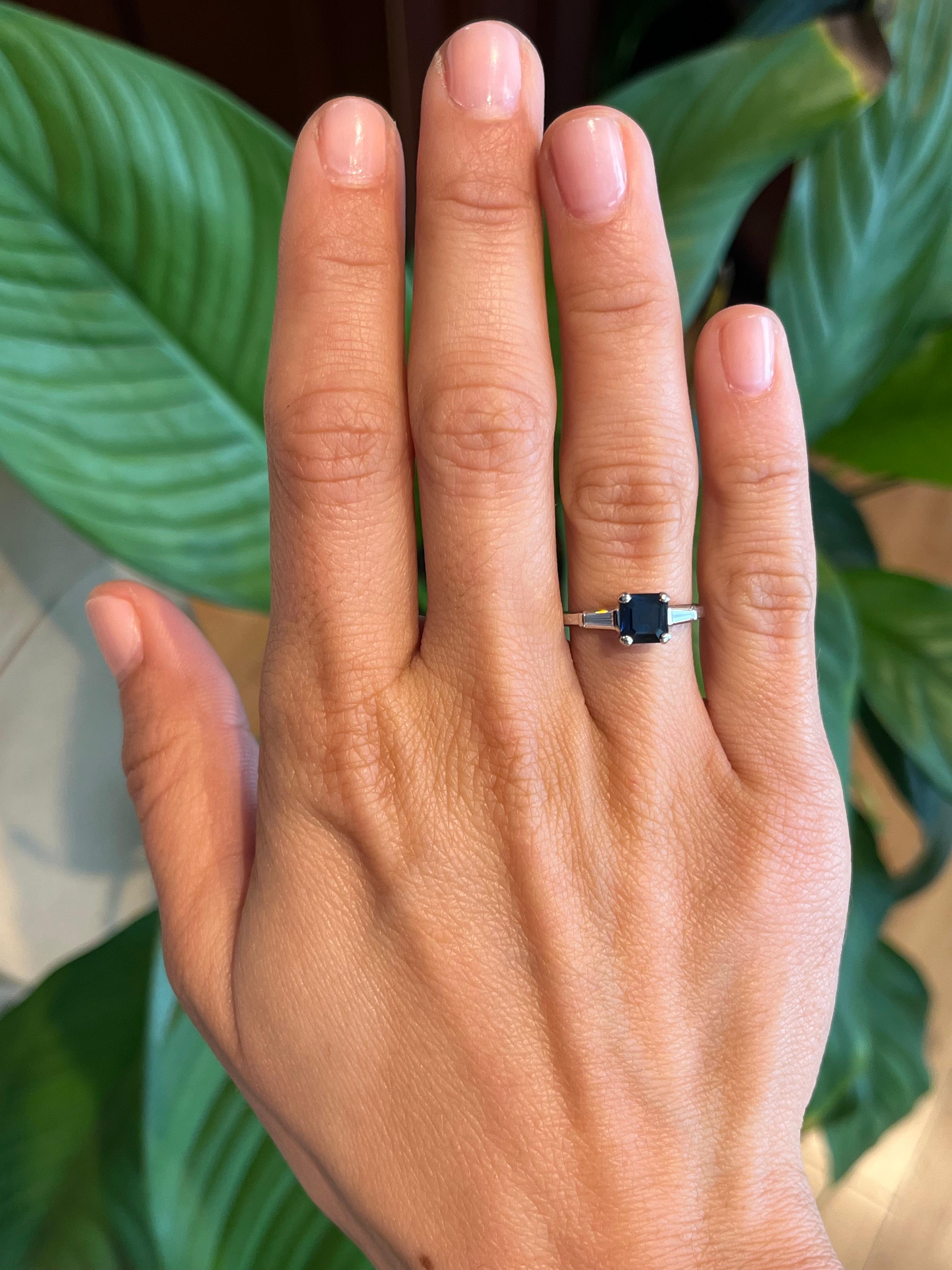 A vintage treasure from the 1950s, this 3-stone engagement ring features a striking 1.13ct square-cut blue sapphire, framed by two baguette-cut diamonds. Crafted in platinum, this refined design exudes sophistication and timeless charm. 

- Circa
