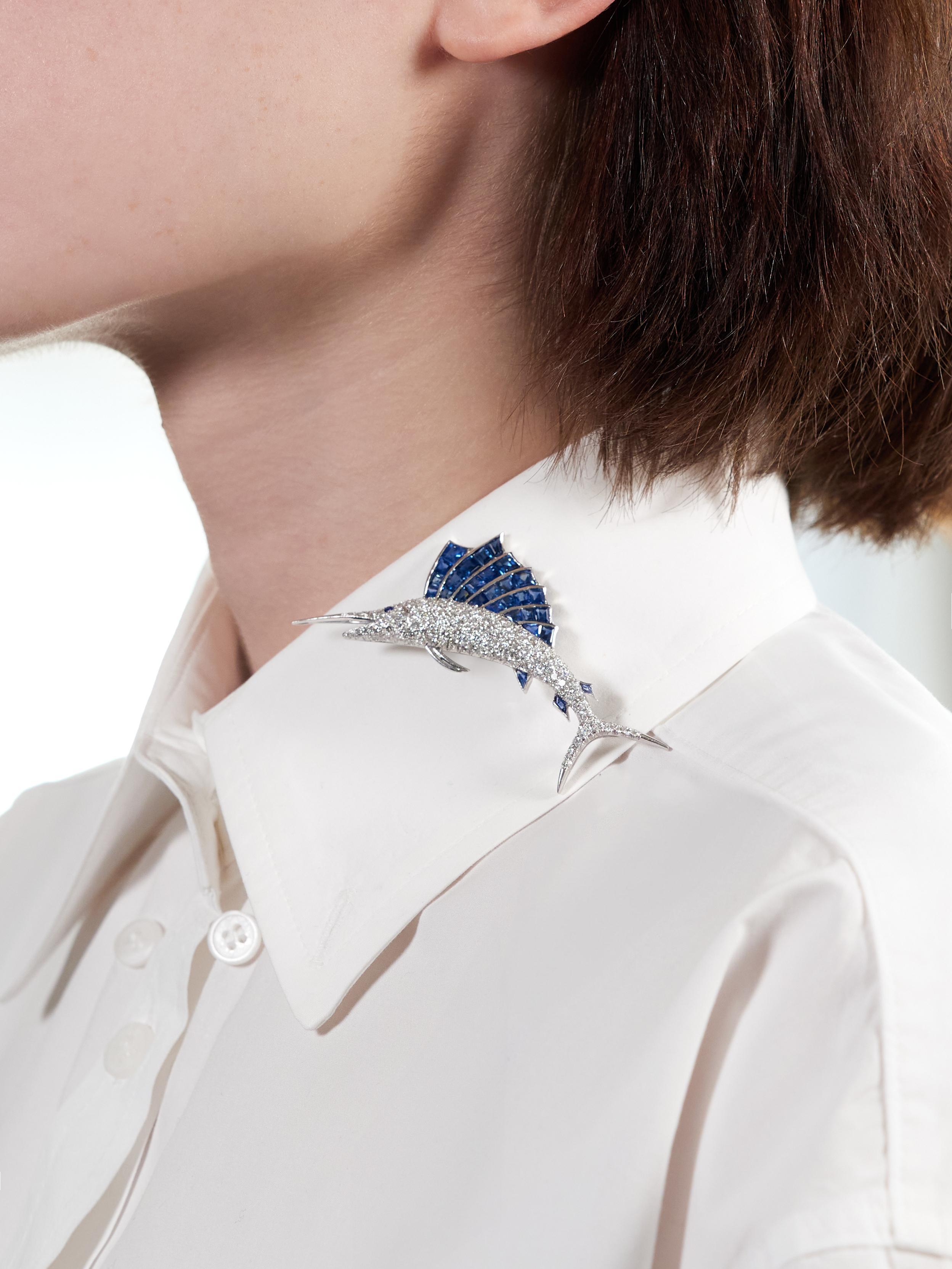Designed as a stylized sailfish with undulating fins and pointed bill
Body is pavé set with round brilliant cut diamonds
Weighing approximately 3.42 carats total - F-G color with VS clarity
Accented by channel set square and mixed cut sapphires in