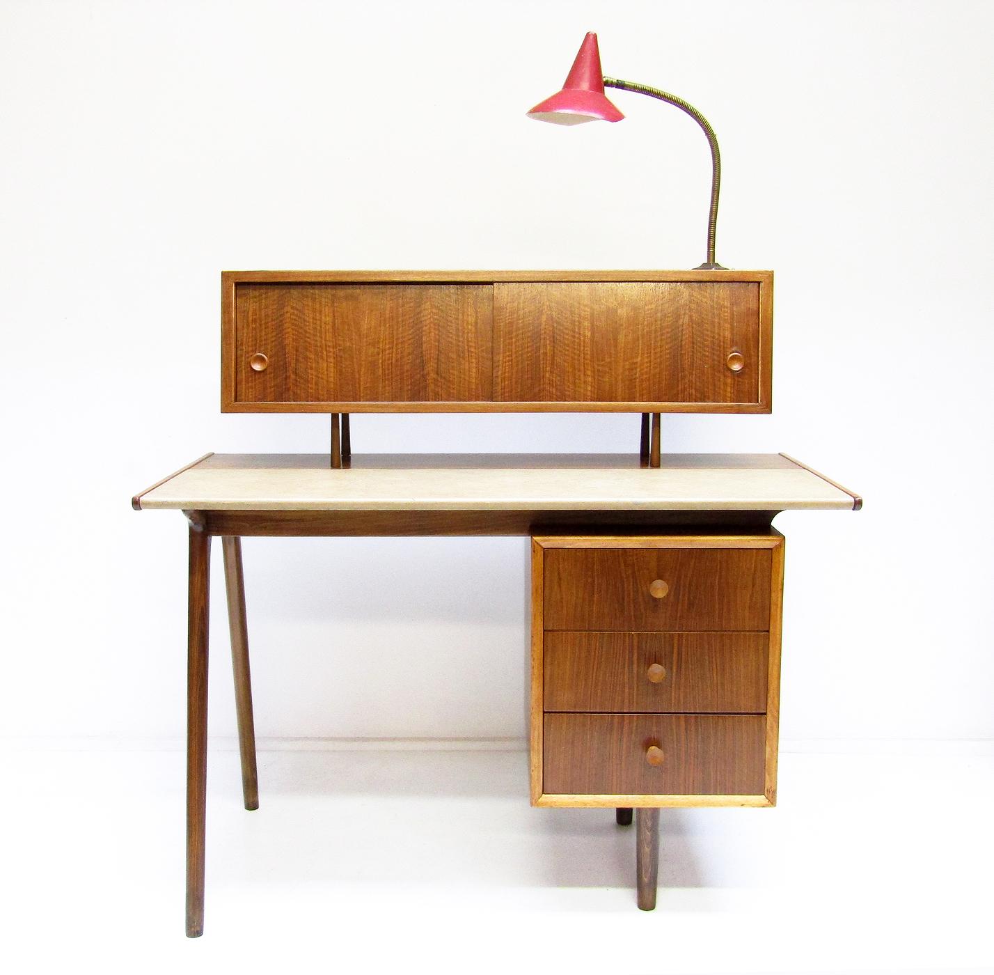 A 1950s atomic desk in walnut and beechwood, attributed to Christopher Heal for Heal & Son.

The combination of floating cabinet, gooseneck lamp, splayed legs and bold walnut figuring make this one of the most appealing desks we have
