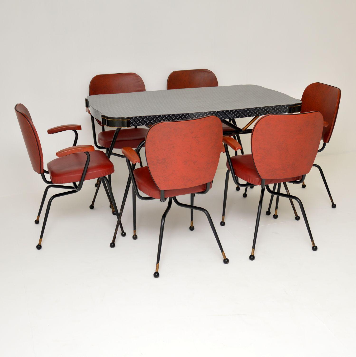 A super stylish and very rare vintage dining table and chairs, dating from the 1950s. The table has a beautiful shape, clean Formica top, and amazing ebonized steel base. The legs have brass accents and terminate in lovely balls. The chairs were