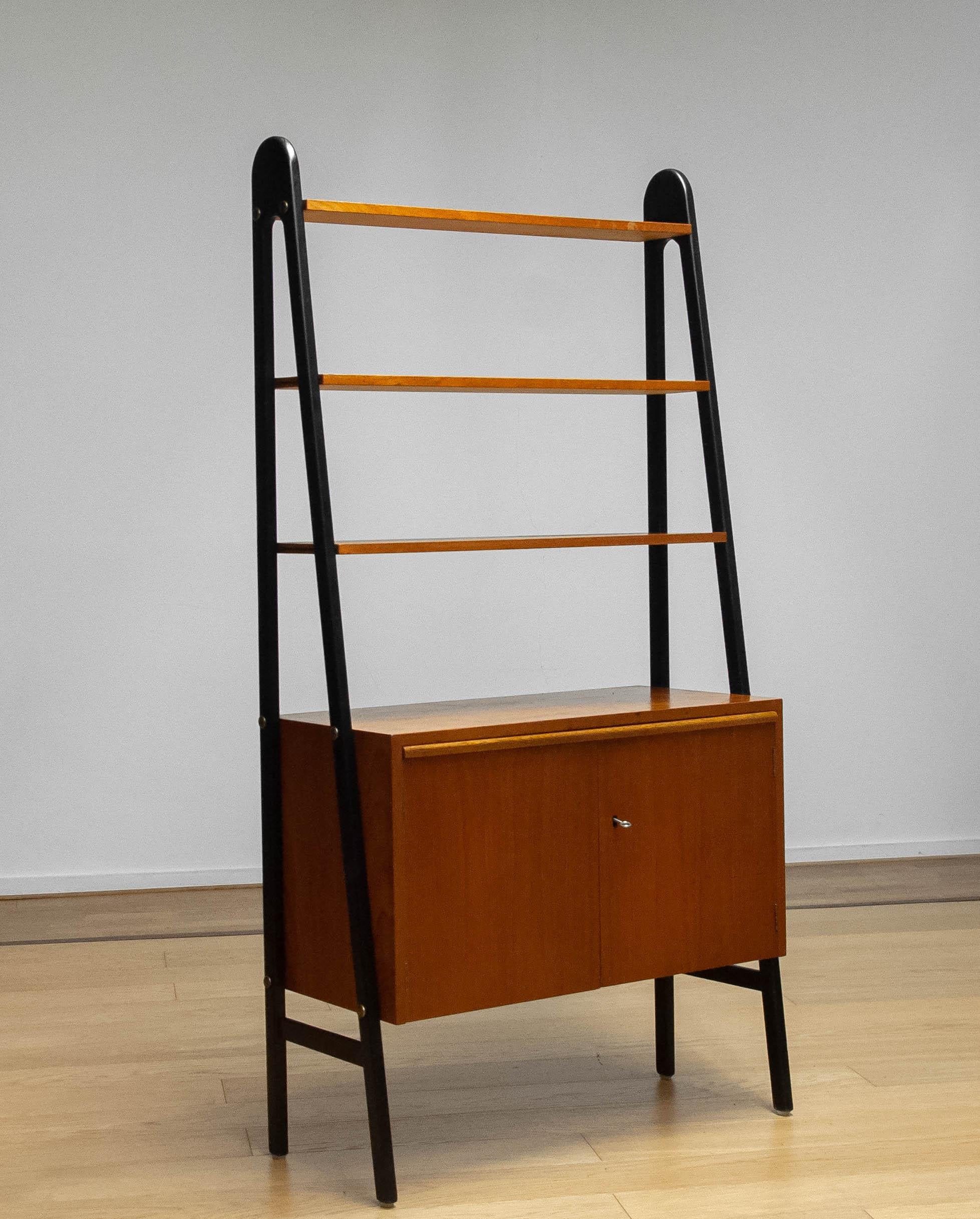 Meuble bibliothèque scandinave très décoratif fabriqué en Suède dans les années 1950.
L'armoire en teck avec les portes verrouillables se compose d'une étagère intérieure fixe.
Les trois étagères du haut sont également fixes mais amovibles.
Ce