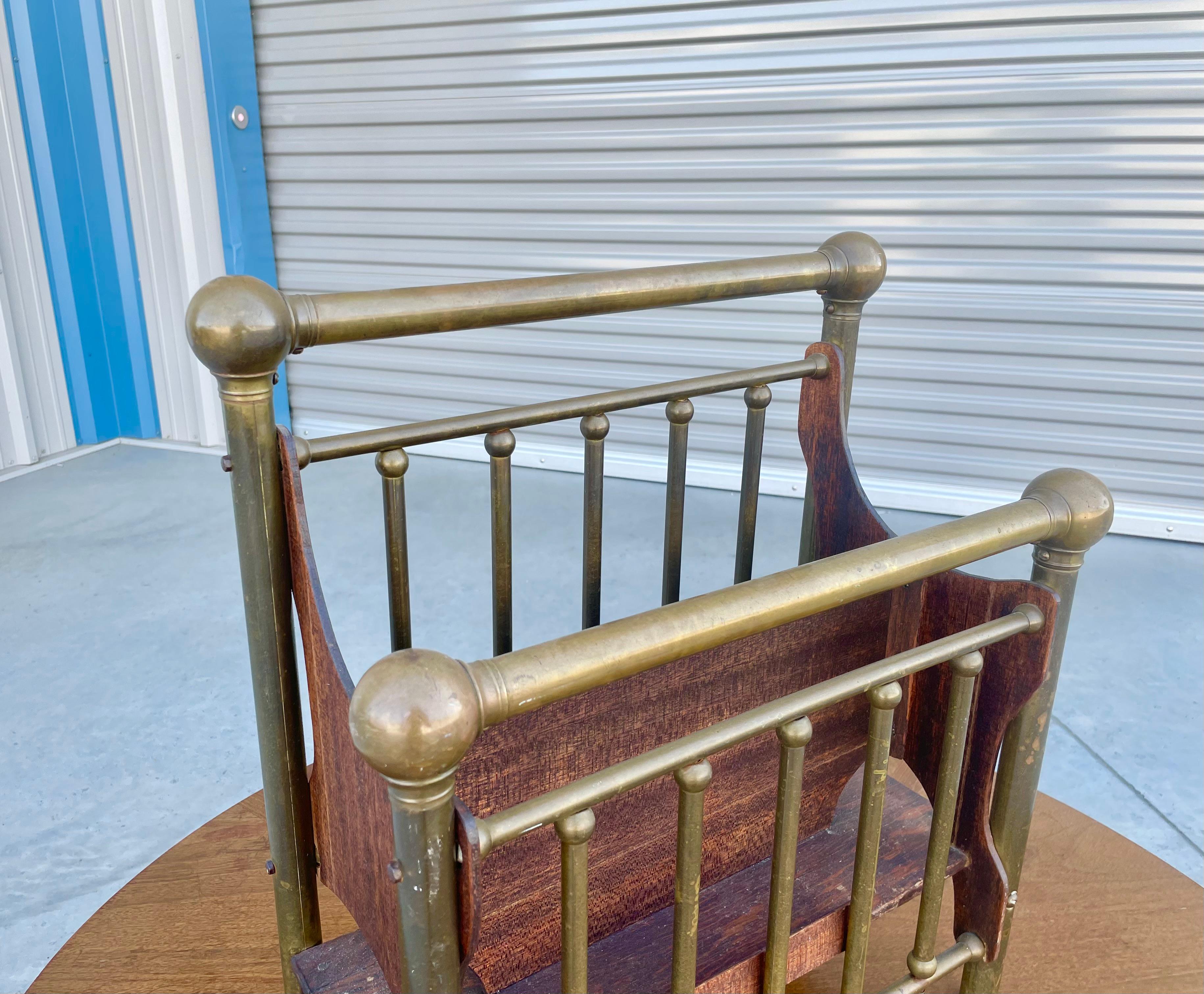 Vintage brass magazine rack designed and manufactured in the United States circa 1950s. This stunning rack features a wooden frame supported by four gorgeous brass legs. What sets it apart, though, are the five brass slats that are located on both