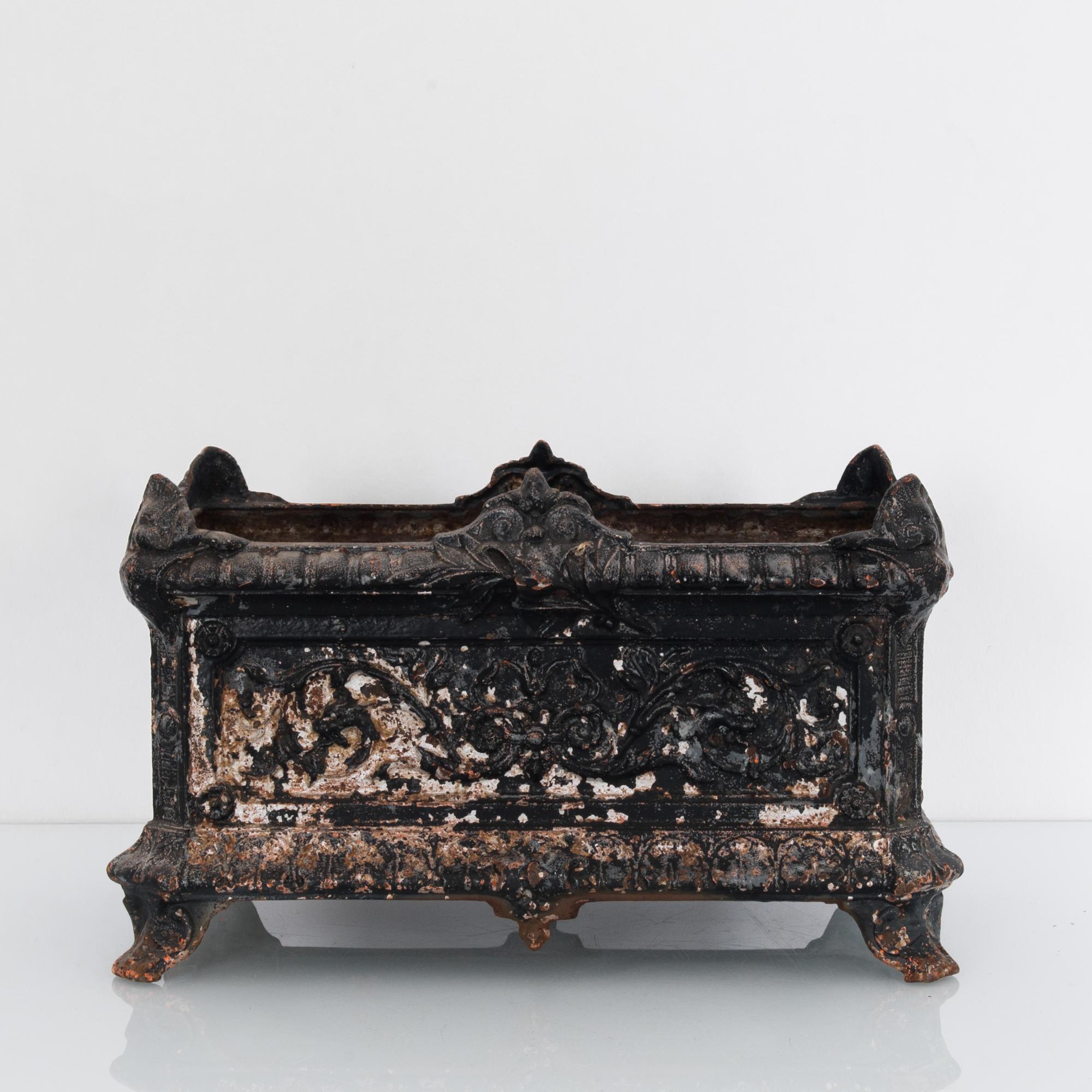 This vintage cast iron planter from 1950s France, features a rectangular shape with decorative accents. The elaborate floral patterns and unique patina of aging black paint produces a muted gothic effect. The sophistication of age gives this vintage