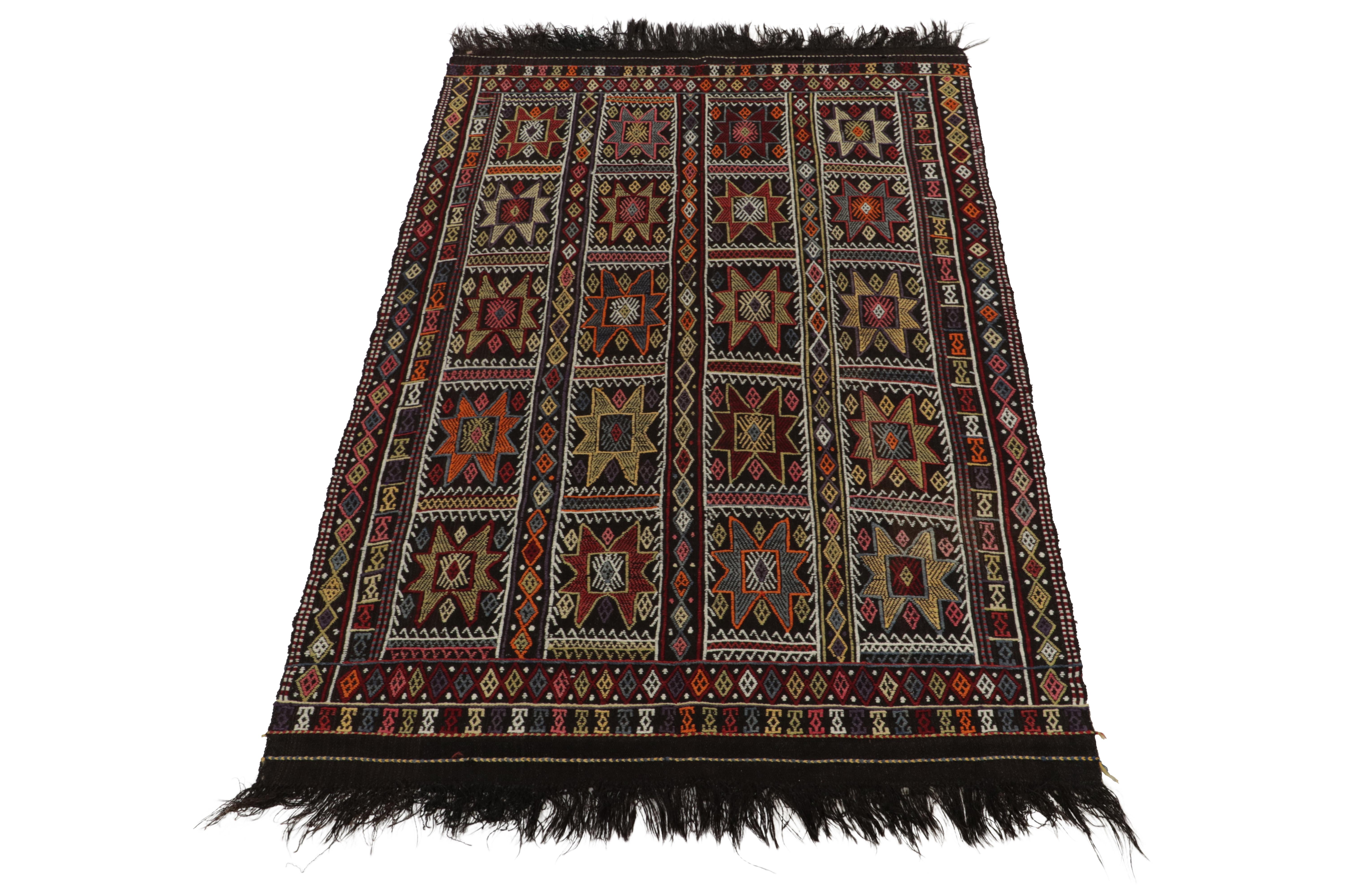 A vintage Kilim rug in 5x8, from the latest curation of the Cecim tribal rug family joining our acclaimed collection. Handwoven in wool from Turkey circa 1950-1960, enjoying a bold near-black background with textural geometric patterns in all-over