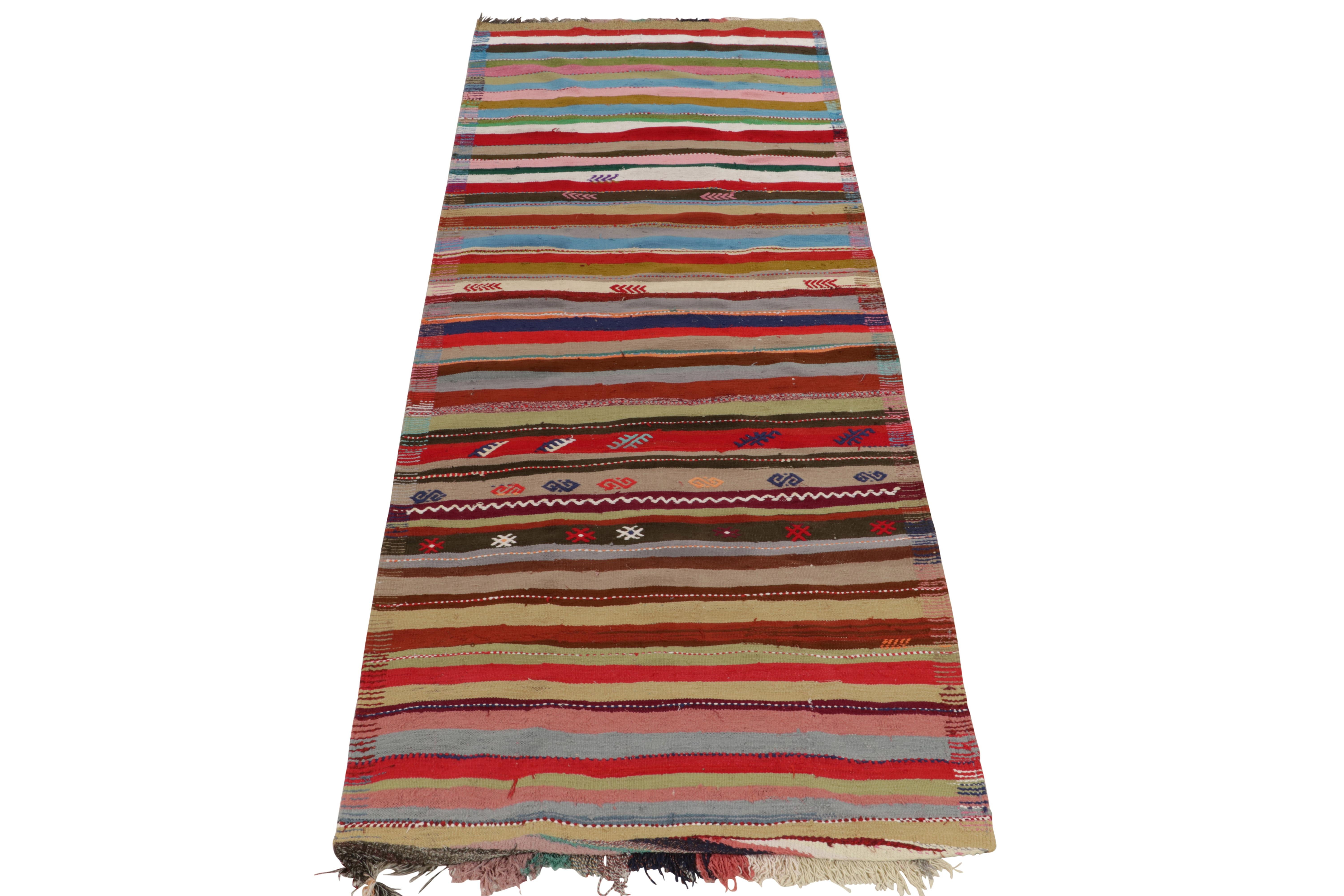 From a distinctive mid-century Chaput Kilim curation, a rare 5 x 12 rug handwoven in wool from Turkey circa 1950-1960. Enjoying a polychromatic, almost rainbow approach to spectral colors with embroidered geometry and tribal motifs. Prevailing red,