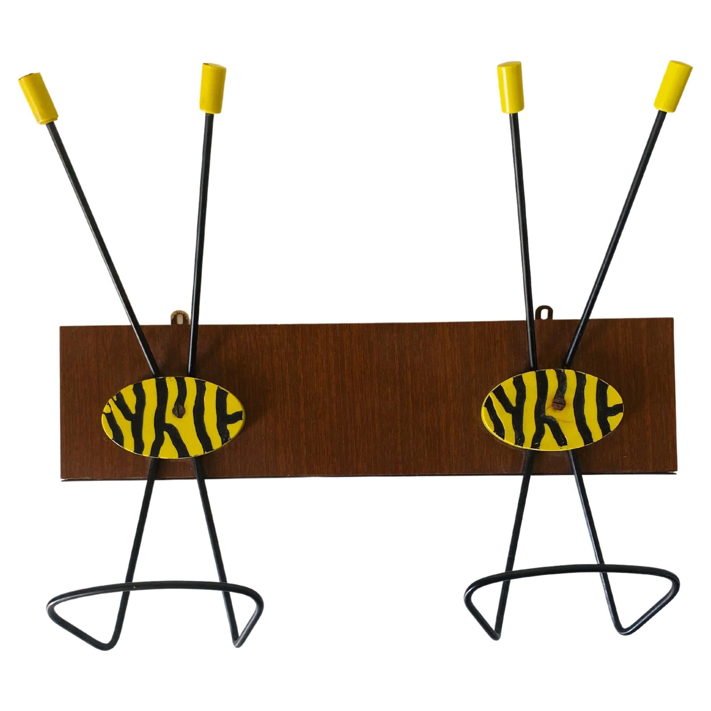 A 1950s vintage coat rack. Teak wood bar with iron rack painted in black and yellow.
In very good conditions with only few signs time.