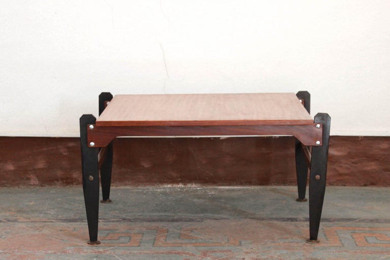 A 1950s Scandinavian coffee table with mahogany wood top, iron structure (painted in black) and brass small feet at the bottom of the legs. The article is sold in remarkable conditions as the it has been polished and cleaned in all its components.