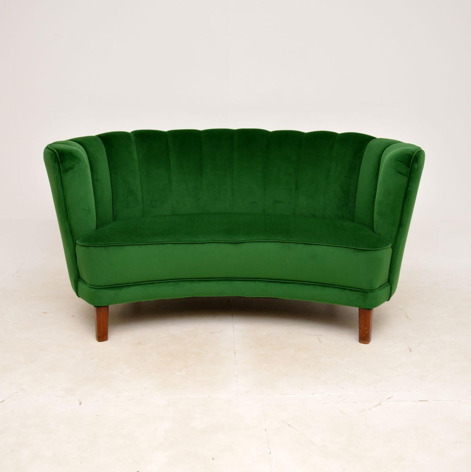 A fantastic vintage Danish curved cocktail ‘banana’ sofa, recently imported from Denmark and dating from the 1950s.

This is of outstanding quality, and is very comfortable. It has a gorgeous shape with a fluted back, and sits on stained beech