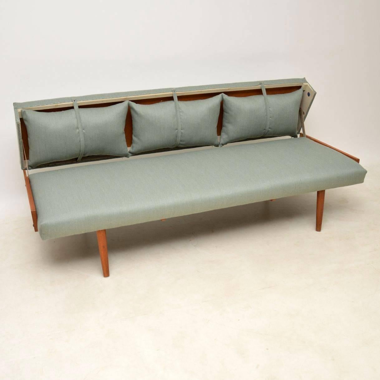 A beautiful and very practical vintage Danish sofa bed, this dates from the 1950s-1960s. This has an unusual design, it comes with three loose cushions that can be used on the front or stored in the back when not needed, held in place by fabric