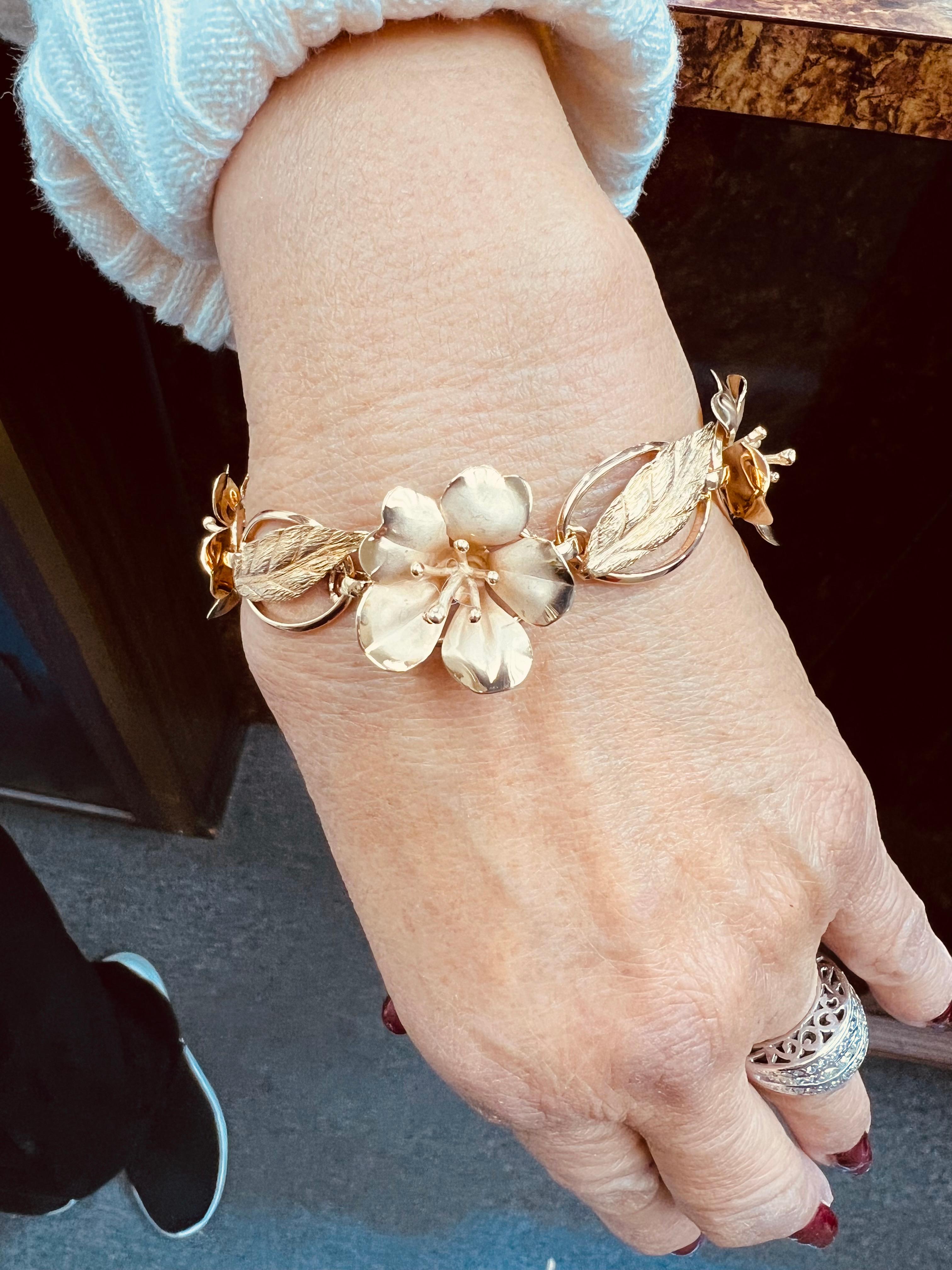 1950er Vintage-Armband aus Gelbgold mit Blumen und Blättern.

Die 1950er Jahre markieren eine bedeutende Periode in der Entwicklung des Schmuckdesigns, die durch eine deutliche Vorliebe für Gelbgold gekennzeichnet ist, insbesondere bei Blumen- und