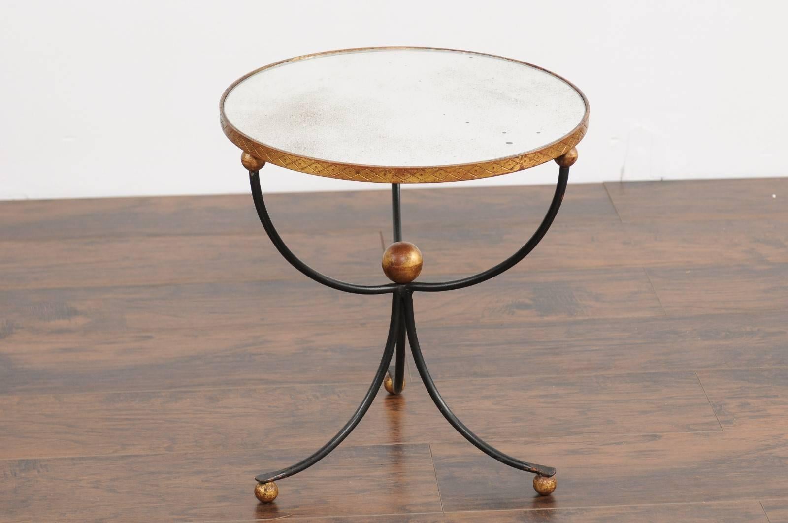 A vintage Italian gilt metal and iron guéridon side table stamped Palladio from the mid-20th century with tripod base and mirrored top. This Italian side table features a circular top, surrounded by a gilt metal frame adorned with incised patterns,