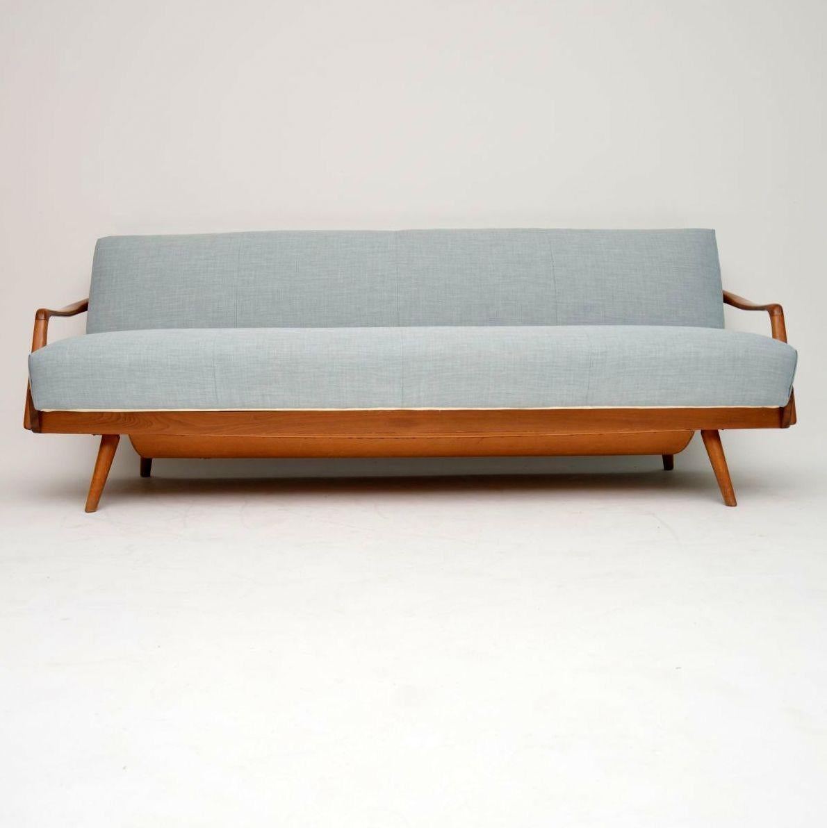 A stunning vintage sofa bed, this was made in France and dates from circa 1950s-1960s. We have had it fully re-upholstered in our lovely light blue fabric. The solid wood frame is a light wood that looks like it could be Ash, it’s clean, sturdy and
