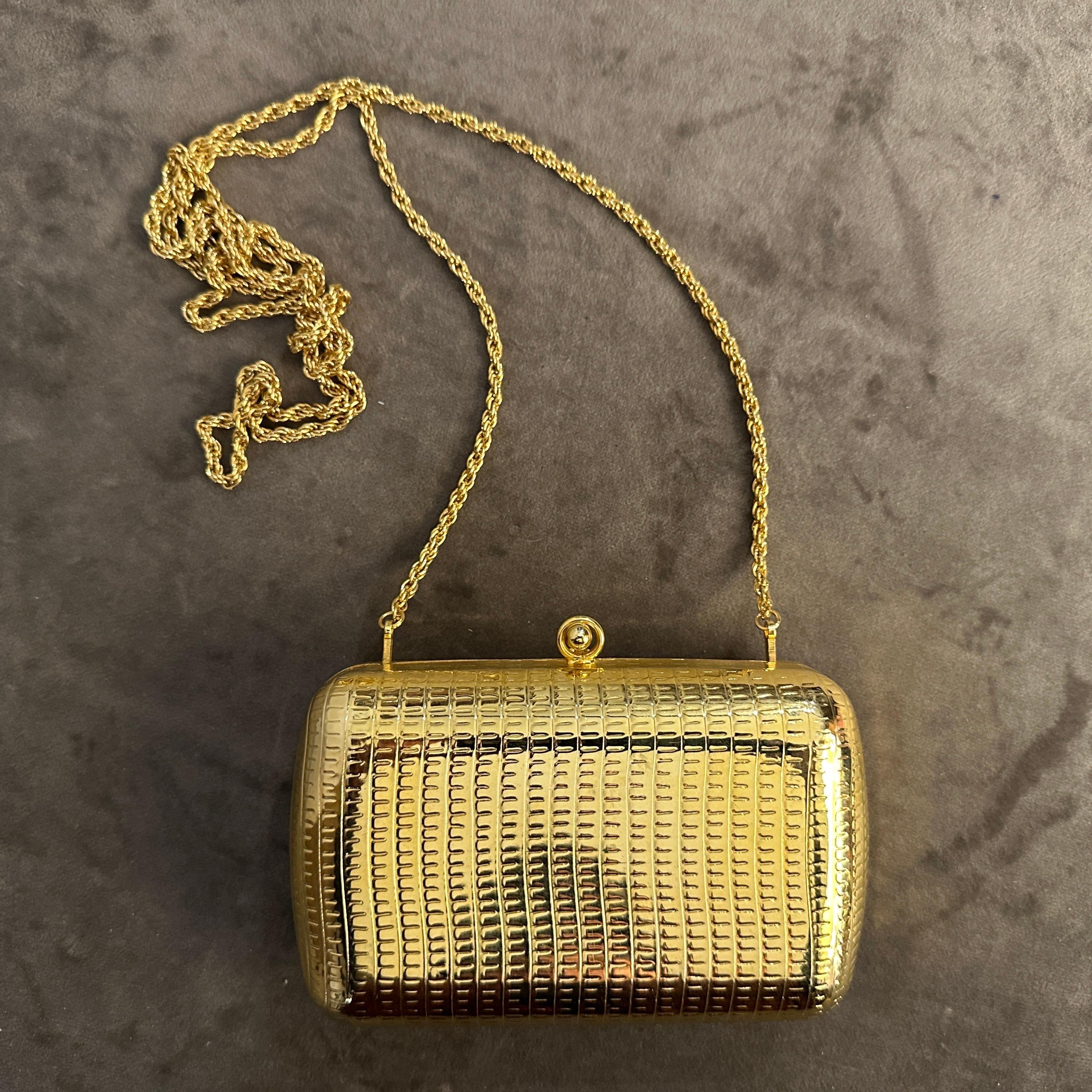 This 1950s vintage Italian evening bag is a stunning example of mid-century elegance. Crafted from gilded metal, it features a rectangular, hard-shell design with a sleek and sophisticated textured finish resembling reptile skin. The bag is adorned