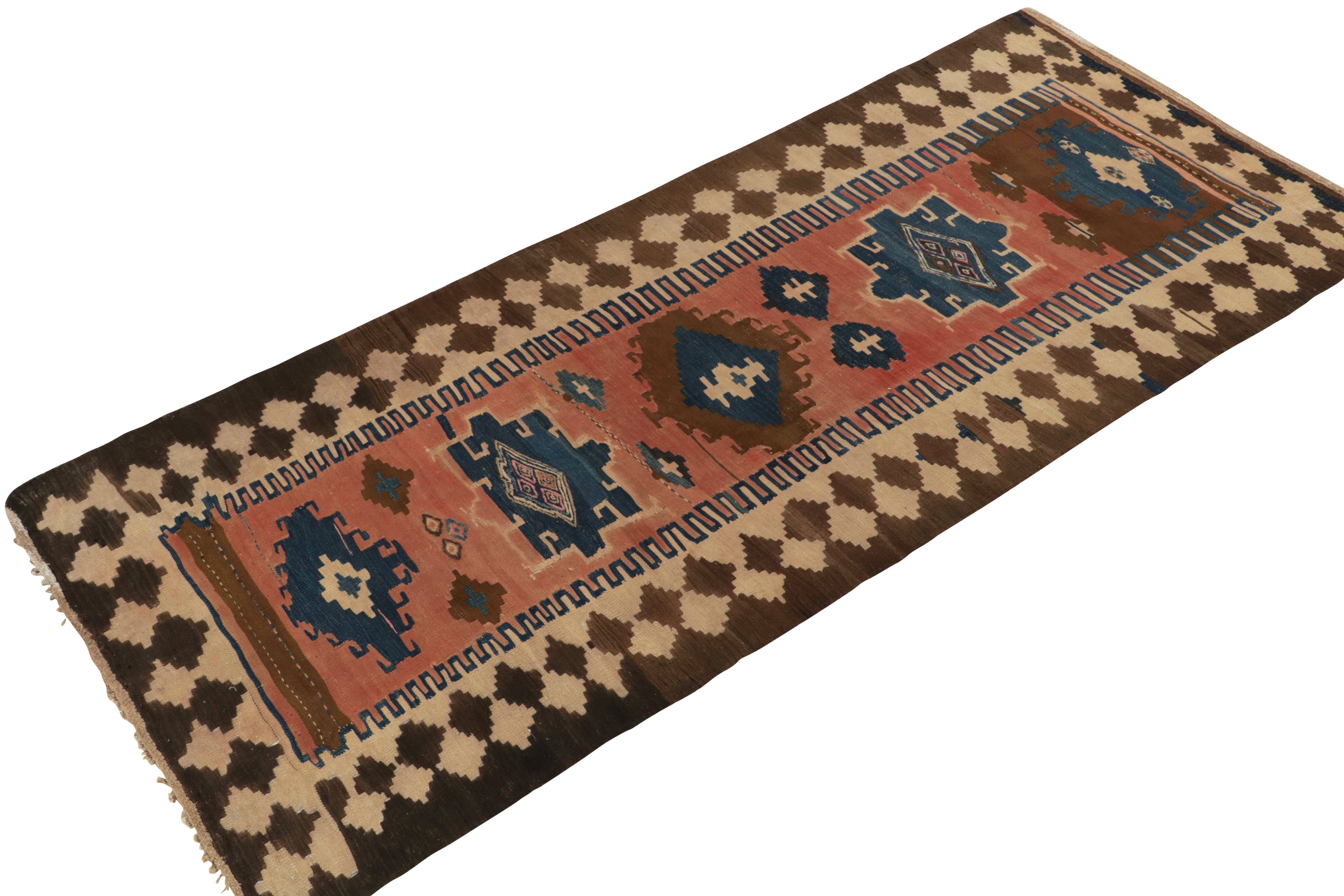 Handwoven in wool from Turkey circa 1950-1960, a unique mid-century kilim rug now joining our vintage flat weaves. 

The most unusual design revels in a rust pink background playing with blue and beige-brown, playing beautifully with the mild