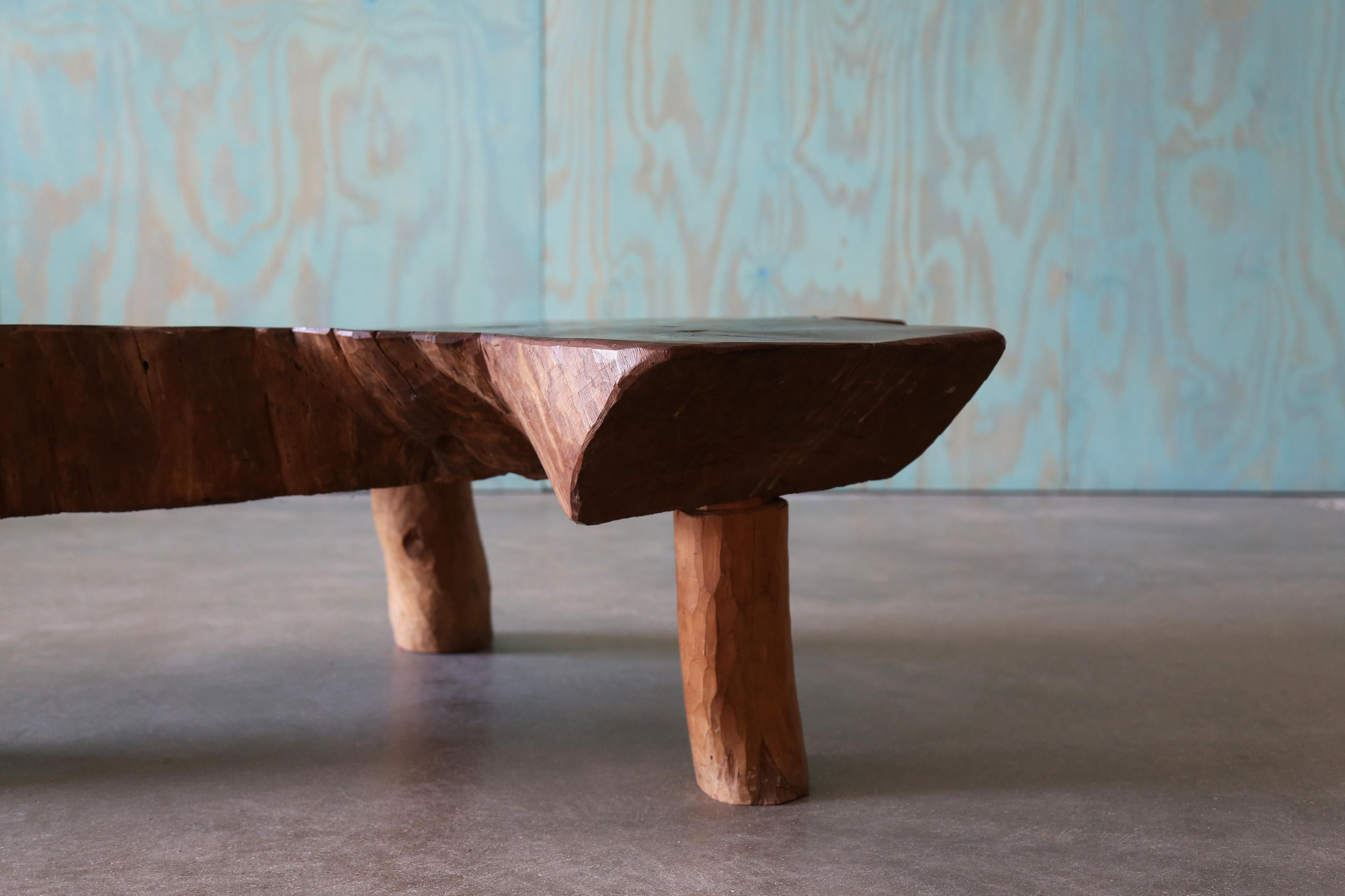 A vintage monumental slab coffee table sitting on three stump legs.  Beautiful warm patina, exposed knots, and three trunks merged to form this massive slab coffee table.  The warm tones and soft edges provide a subtleness offset by the large