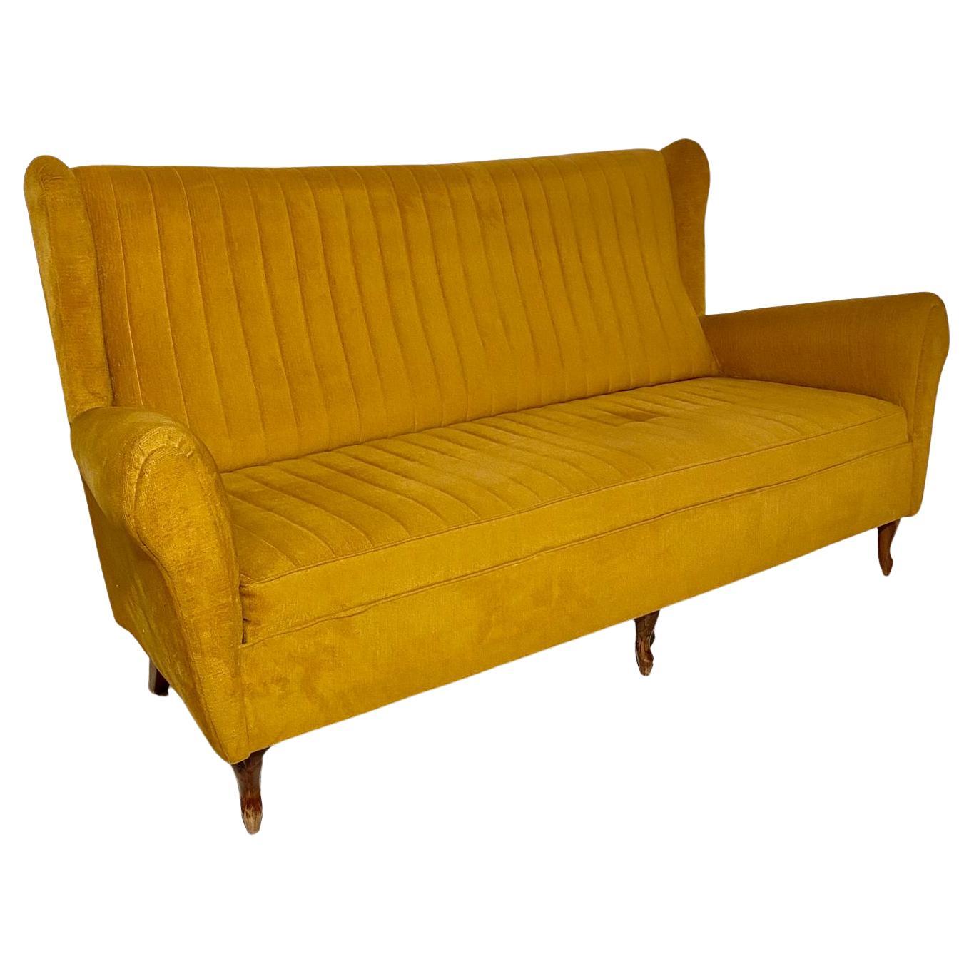 A beautiful and unique mustard-colored Gio Ponti style living room set from the 1950s. Original fabric and curved wooden legs. The set consists of an elegant three-seater high-back sofa and two high-back armchairs. Attributed to Italian design