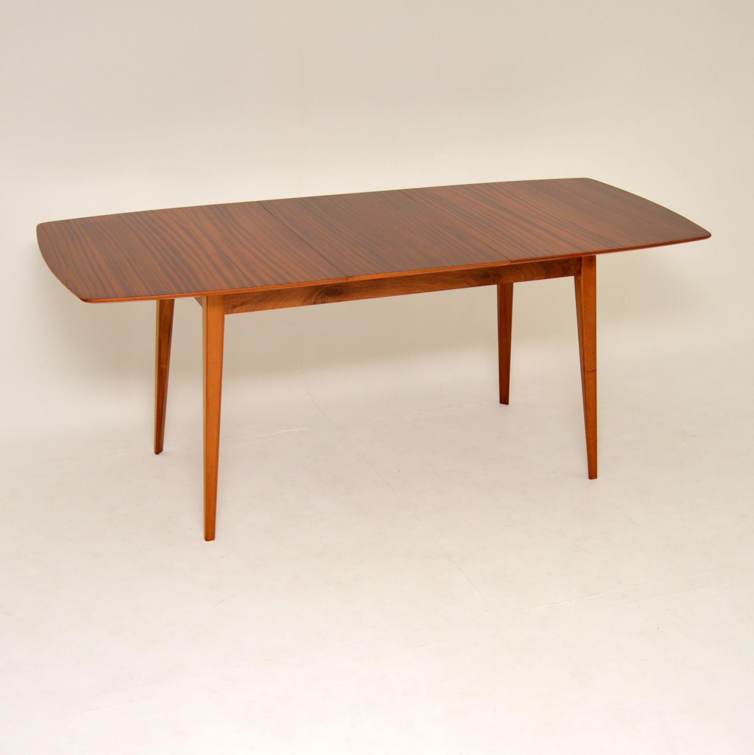 A stylish and very well made vintage dining table, beautifully made in mahogany. This was designed by Peter Hayward, it was made by Vanson in the 1950s-1960s. This has an extra extension leaf to increase the dining area, this is stored beneath the