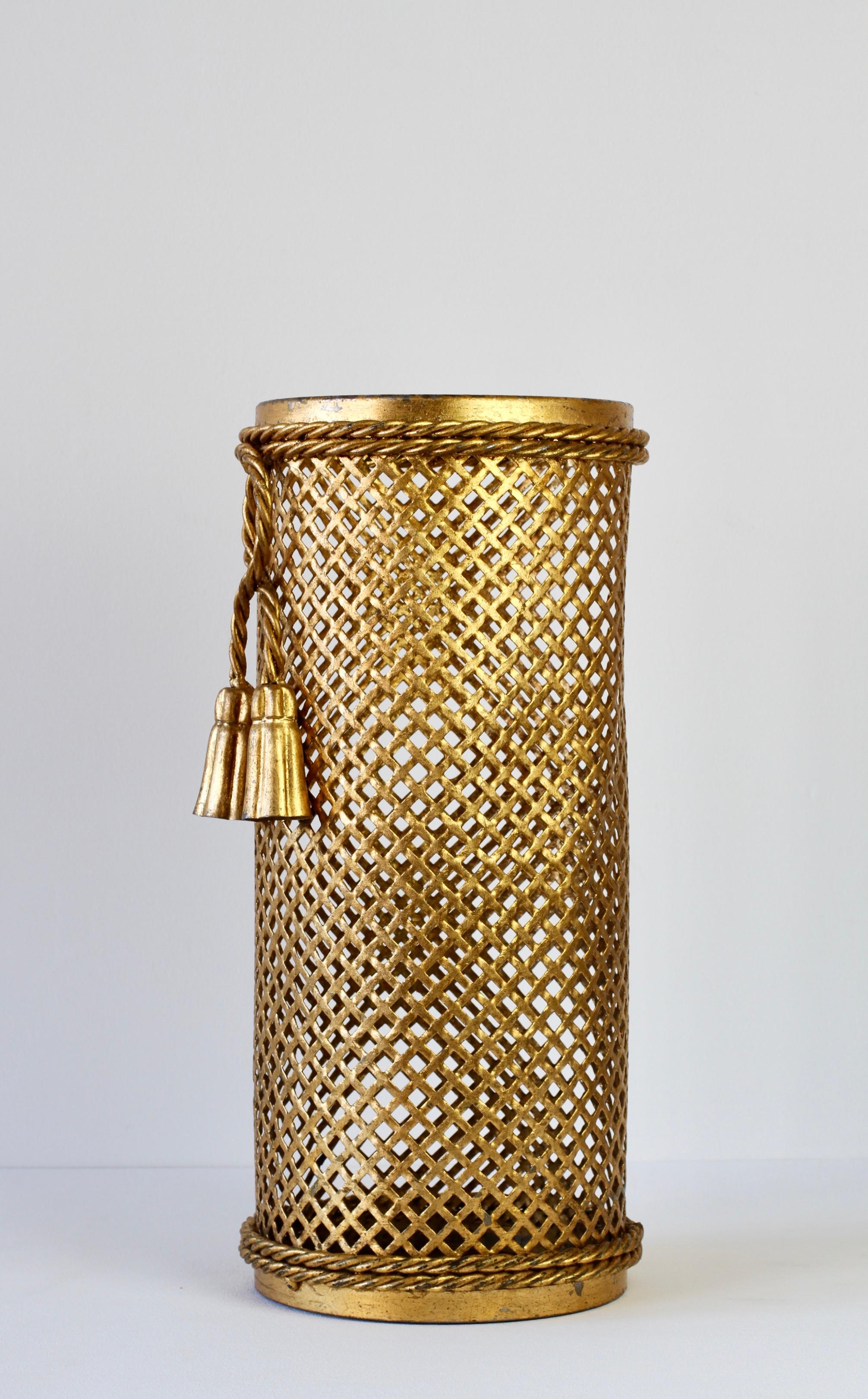 Stunning midcentury gold / gilt / gilded Hollywood Regency style umbrella stand / holder made in Florence, Italy, circa 1950 attributed to Li Puma Firenze. The perforated lattice patterned metalwork with bent rope and tassel details finishes the