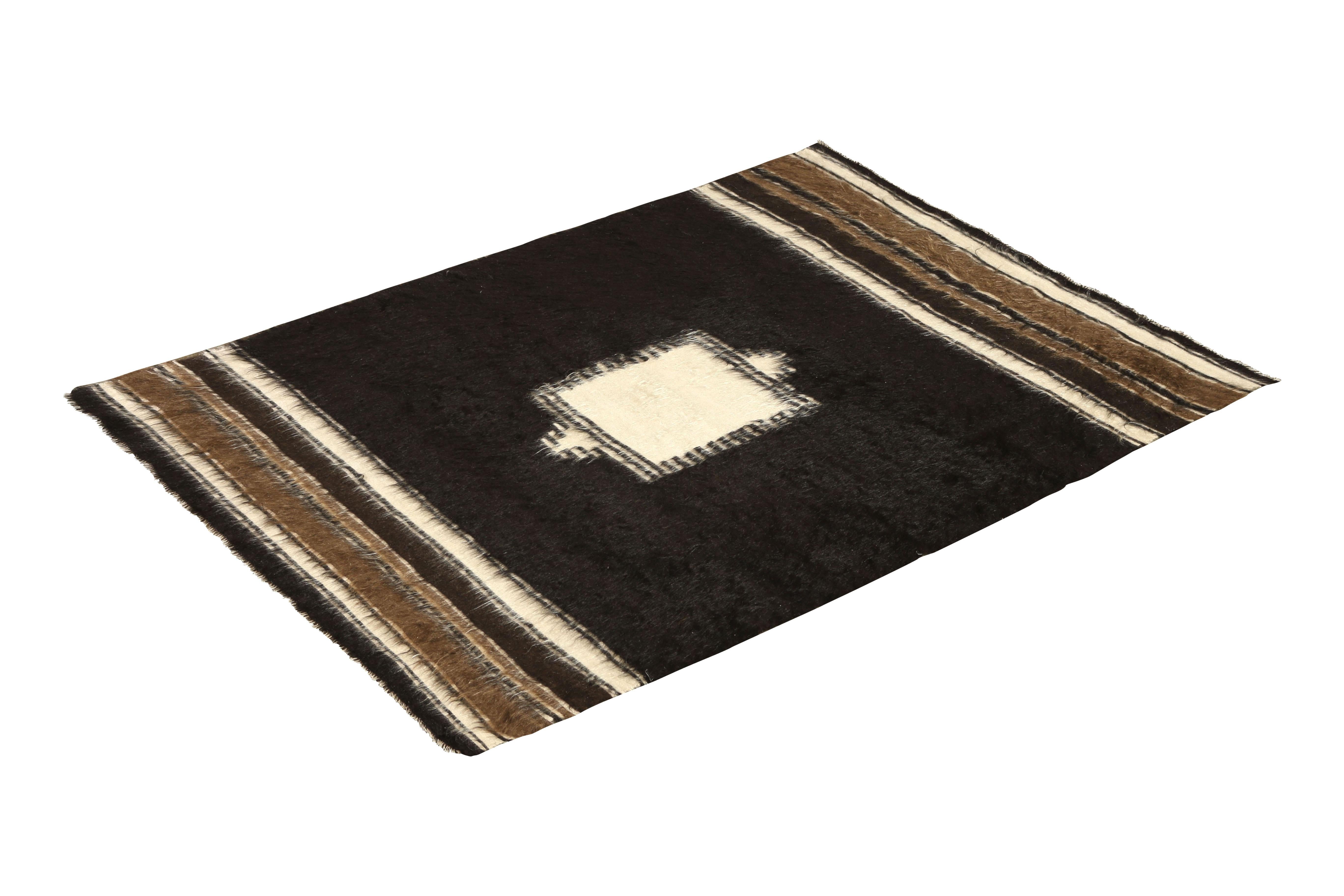 Handwoven in wool originating from Turkey circa 1950-1960, this midcentury vintage Kilim enjoys the combination of multiple rare design features, particularly a special yarn creating the almost shag texture in the field and striped borders as well