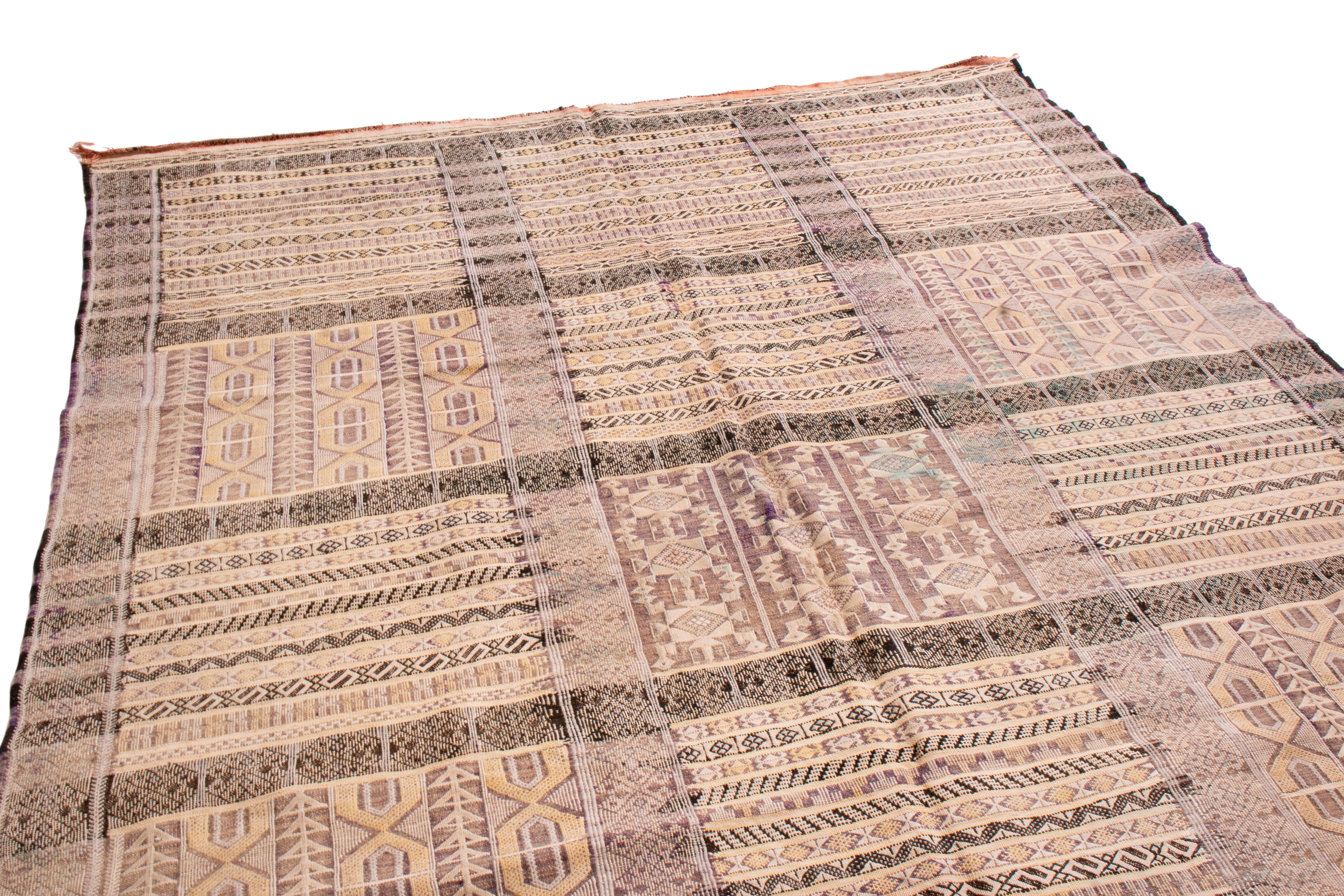 Handwoven in wool originating from Morocco circa 1950-1960, this vintage flat-weave connotes a midcentury Moroccan Kilim design, reversible with two distinctive sides in this play of beige-brown and purple hues with bold black and yellow accents.