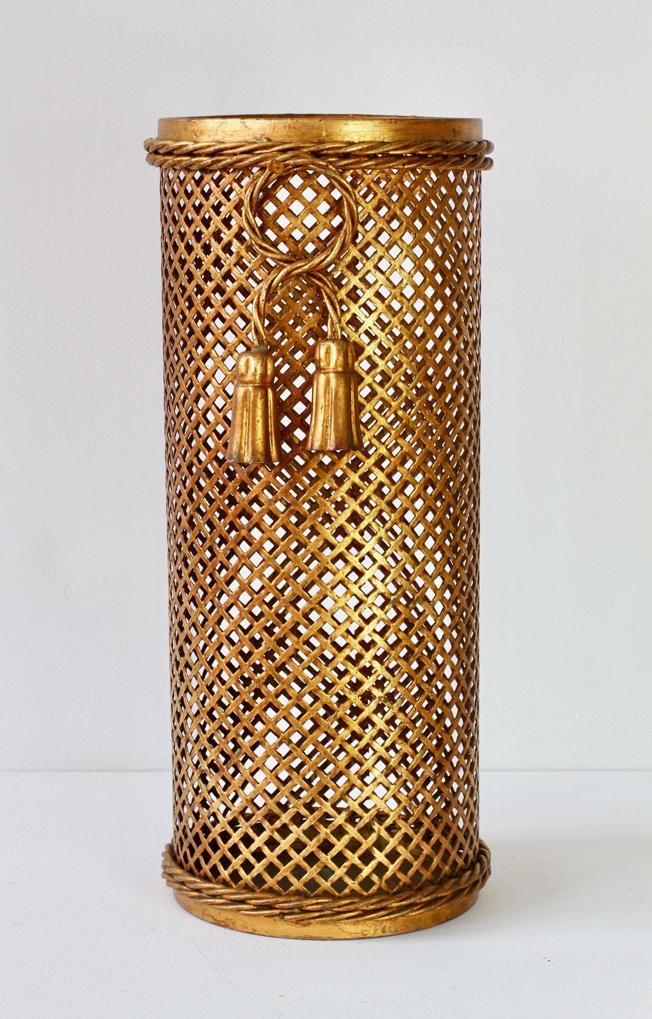 Stunning midcentury gold / gilt / gilded Hollywood Regency style umbrella stand / holder made in Florence, Italy, circa 1950 attributed to Li Puma Firenze. The perforated lattice patterned metalwork with bent rope and tassel details finishes the