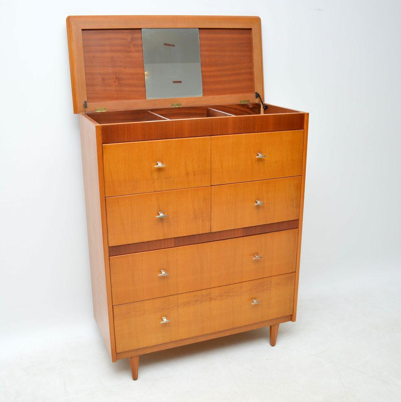 A large and very stylish vintage chest of drawers in oak and walnut, this dates from the 1950s. It’s a very useful piece, with lots of storage space. A great feature of this, is that the top flips up to reveal a mirror and further compartments for
